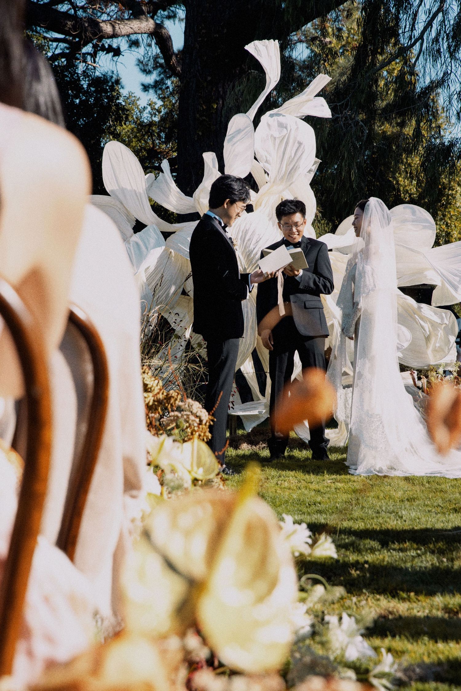 An outdoor wedding ceremony setup with white decorative elements and floral arrangements.