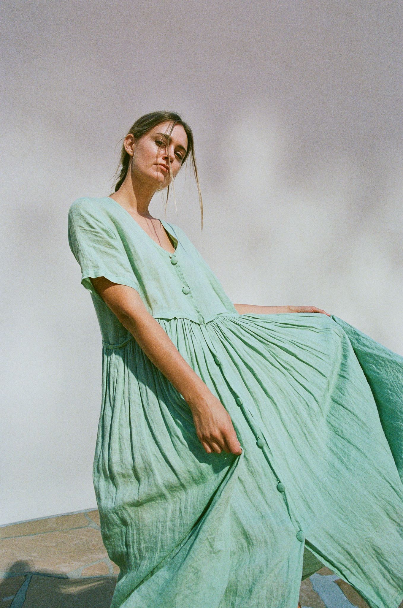 A mint green maxi dress billows gracefully in an artistic fashion photography setting.
