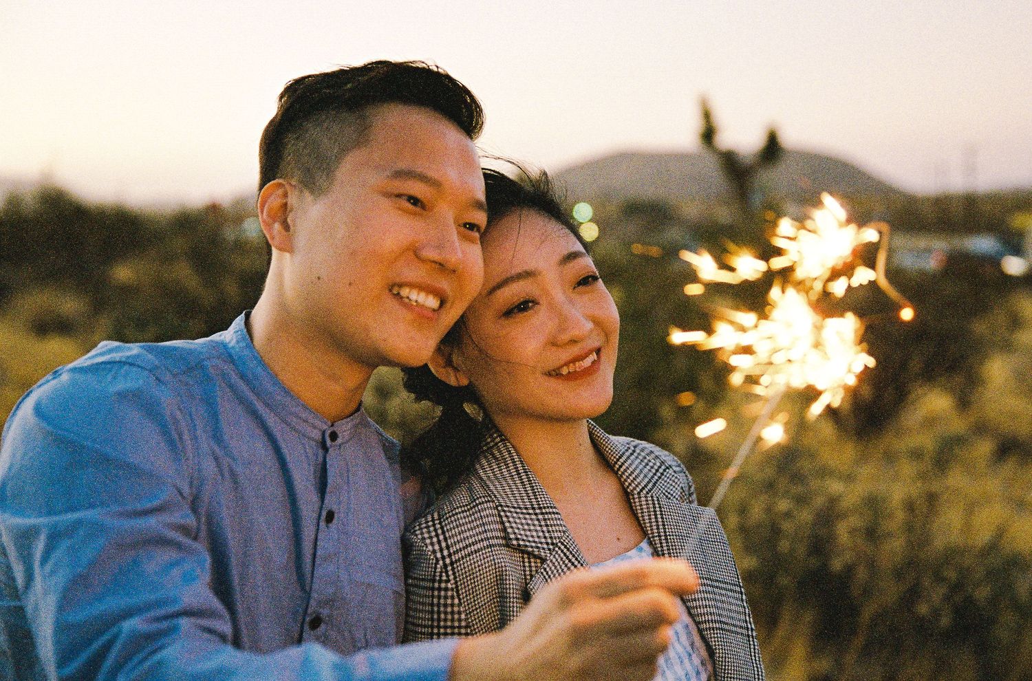 A couple celebrates with sparklers at dusk in the desert.