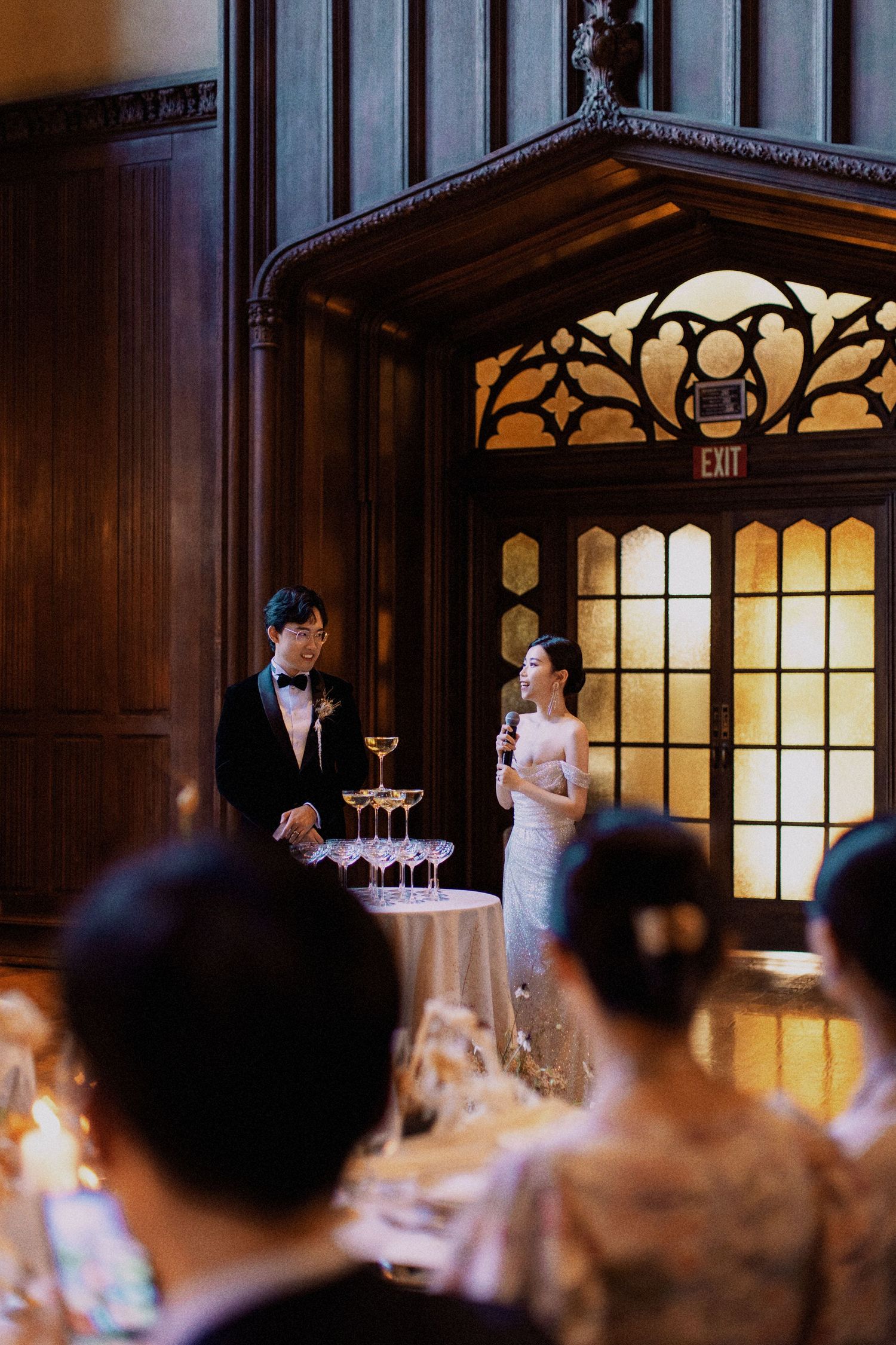 A wedding reception toast in a grand wood-paneled room with ornate architectural details.