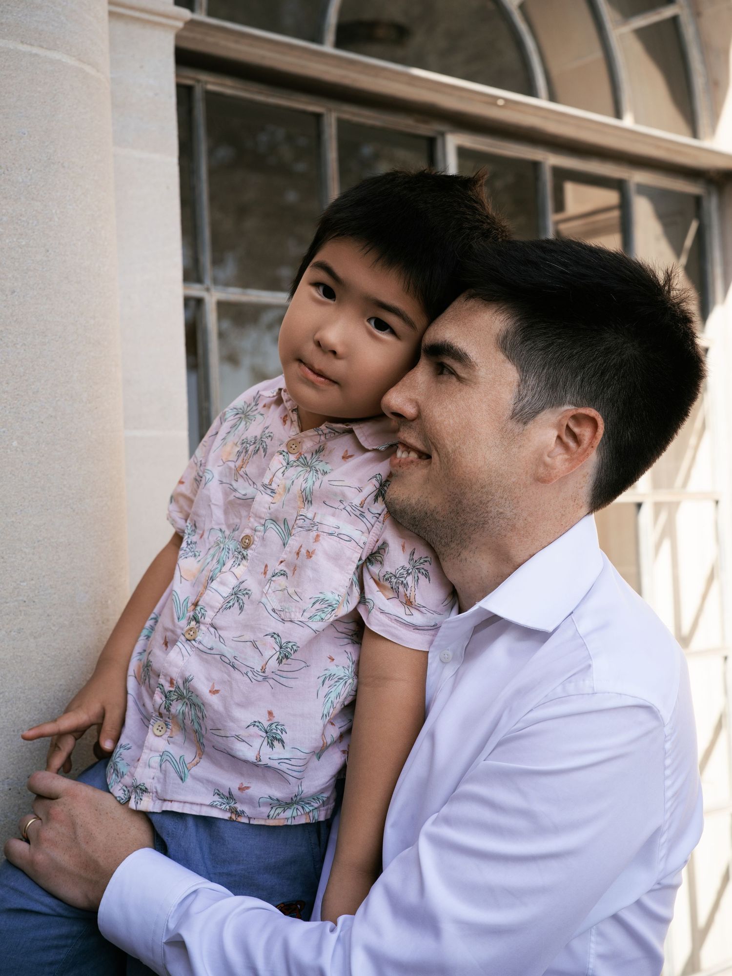A tender moment of bonding between family members outdoors near a building entrance.