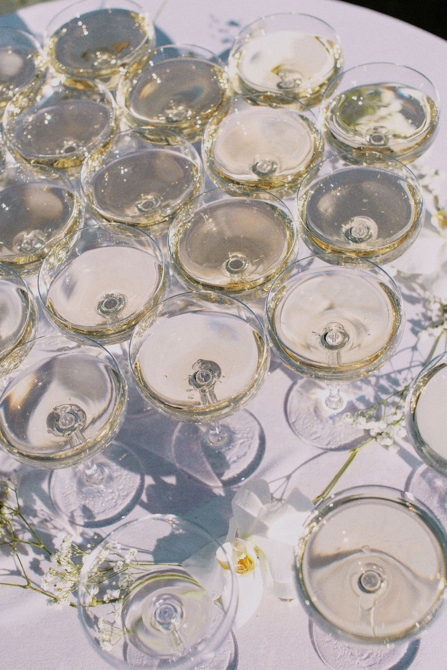 Elegant champagne glasses arranged on a white tablecloth at a wedding reception.