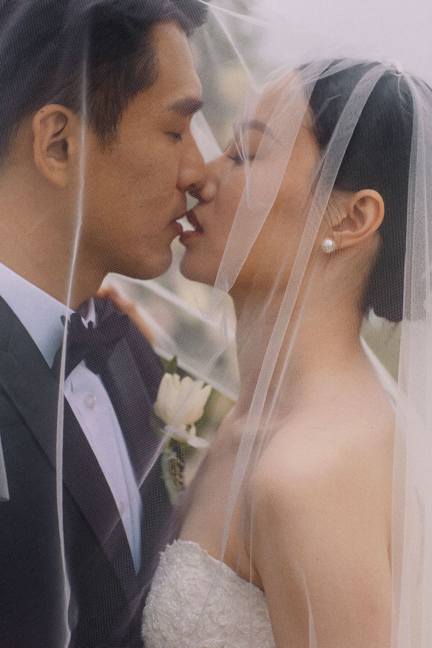 A romantic wedding portrait of a couple sharing an intimate moment under a delicate veil.
