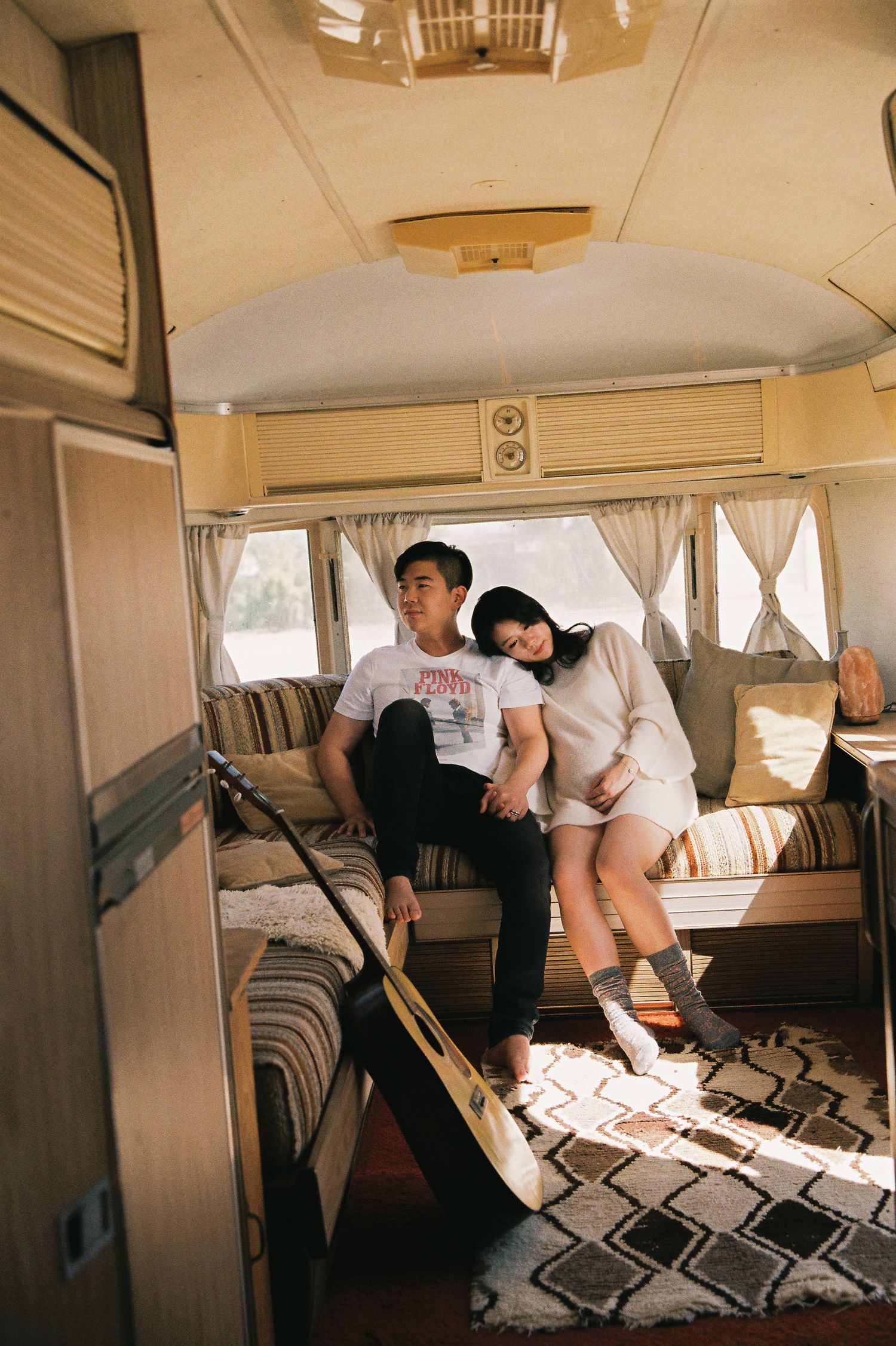 Casual couple lounging in retro camper van with geometric pattern bedding.
