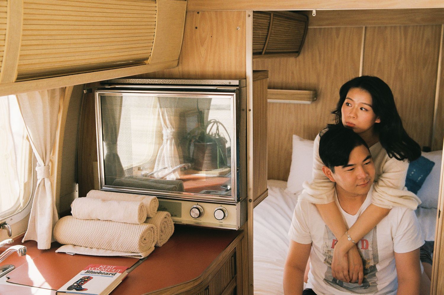 Vintage style photo of couple watching TV inside retro camper van.