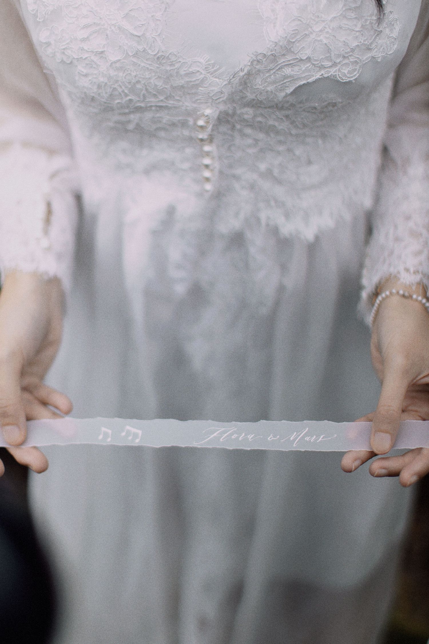 Detailed view of a white lace wedding dress bodice with pearl button details.