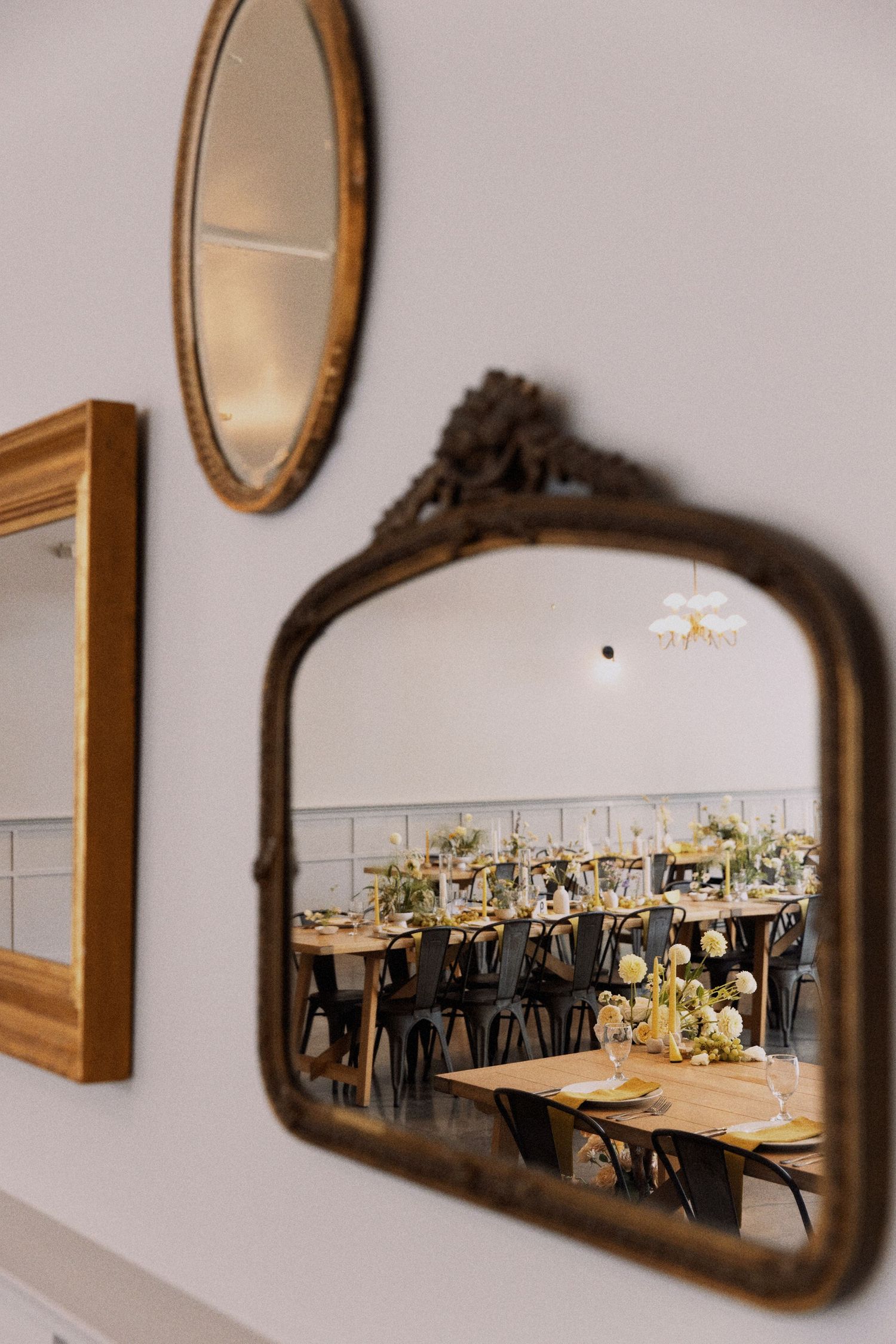 Reflection of an elegant wedding reception setup seen through an antique framed mirror on wall.