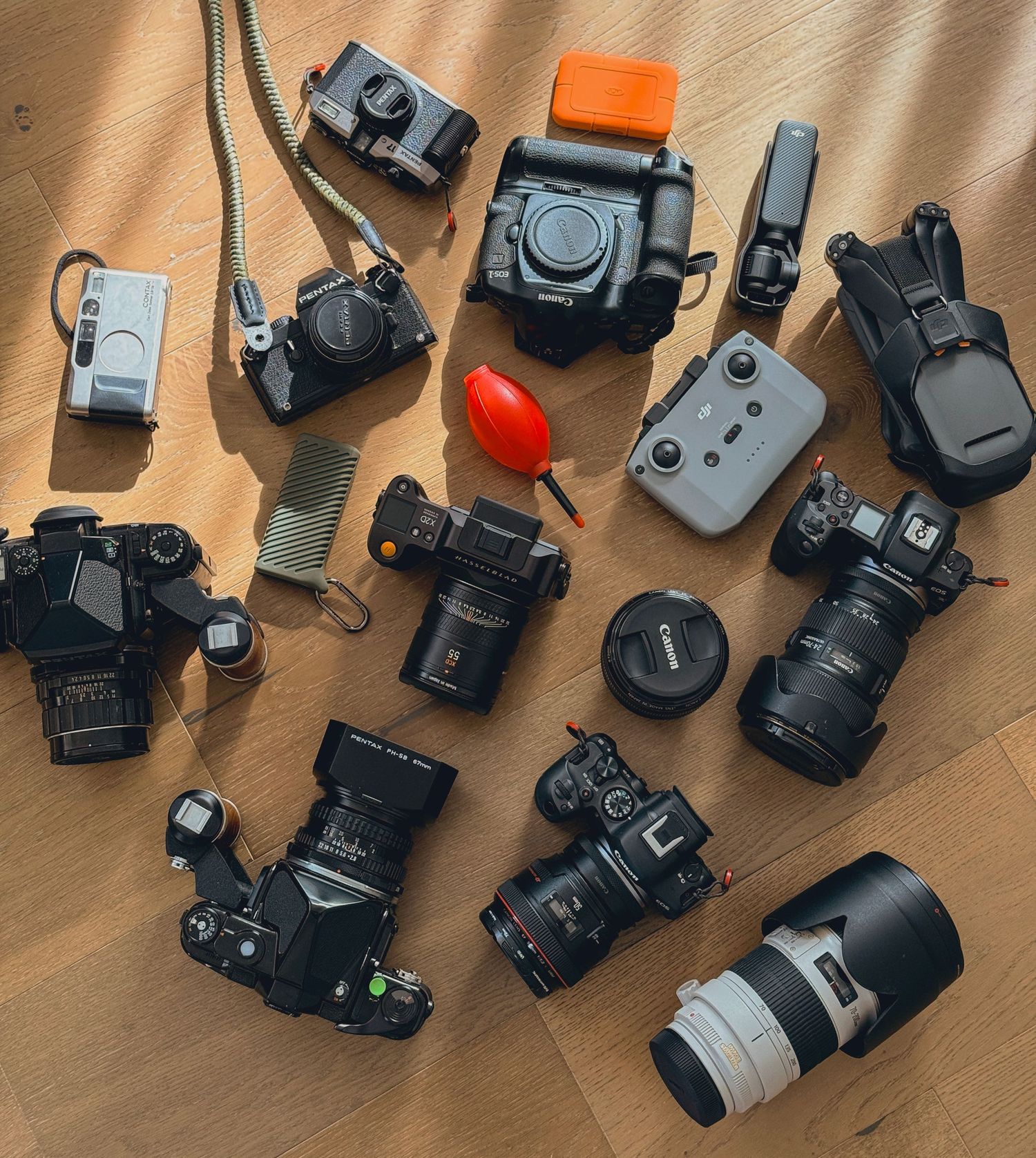 Collection of professional cameras and photography equipment laid out on wooden surface.