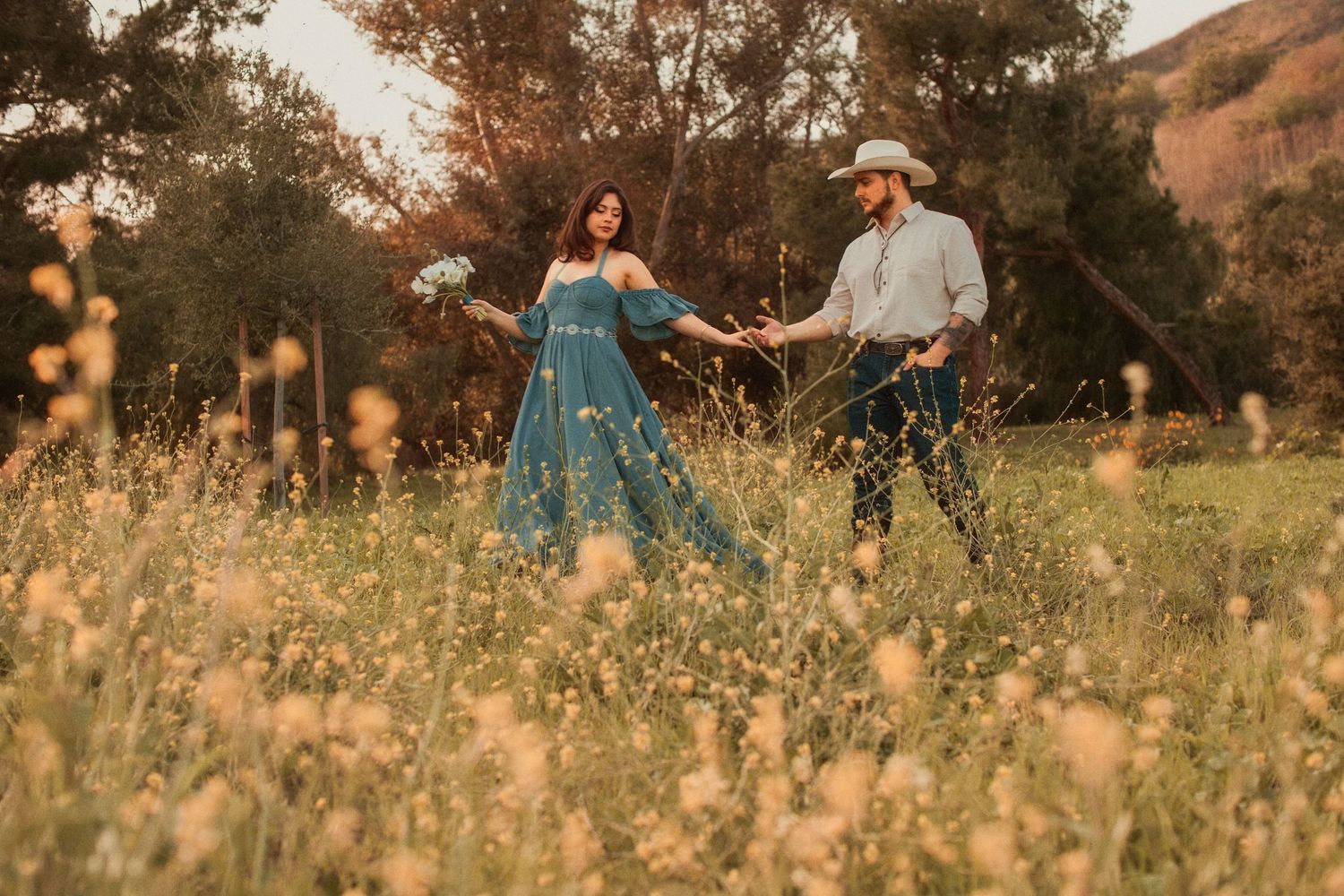 A couple dances in a wildflower meadow at sunset with mountains in the background.