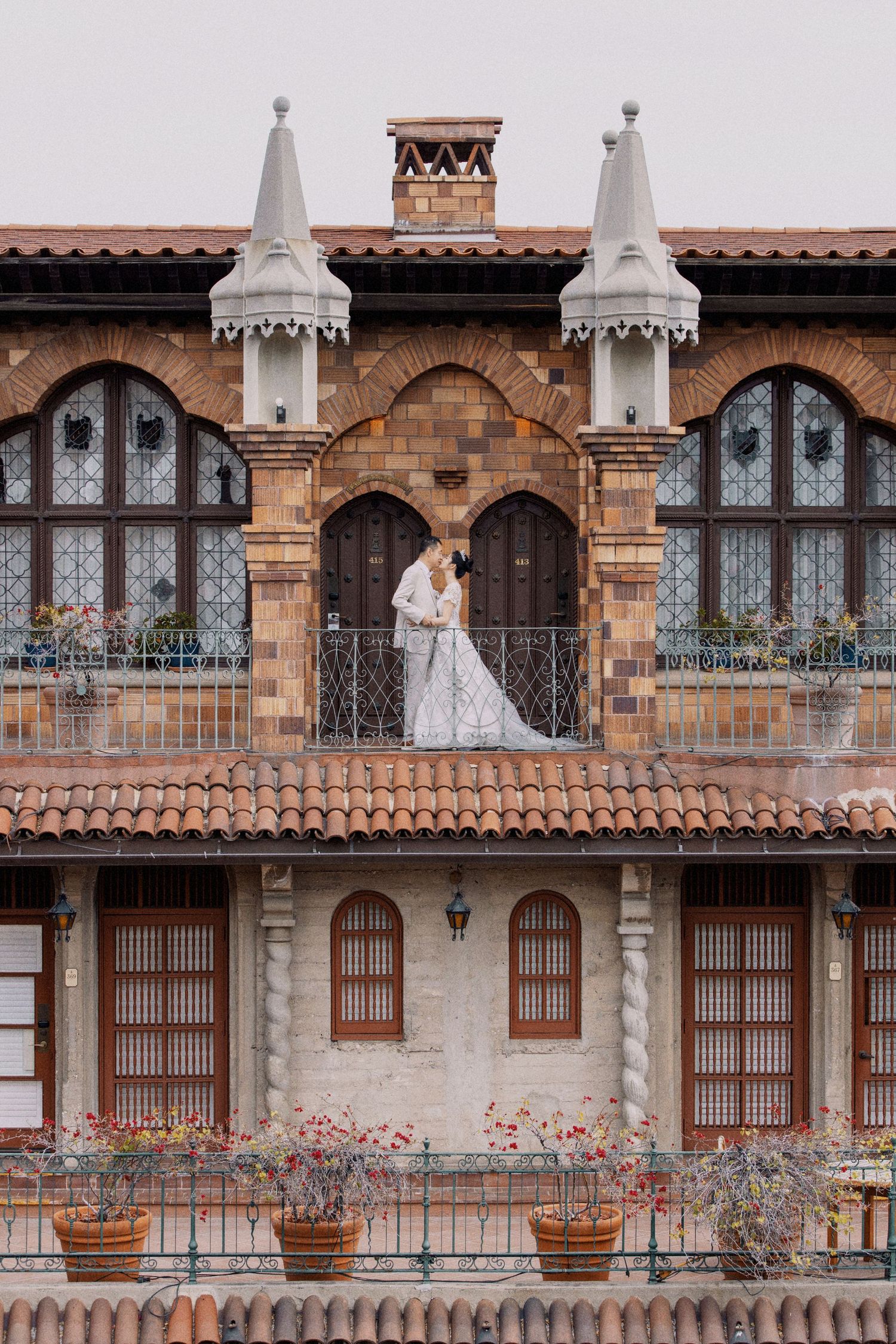 A romantic wedding portrait on a Spanish-style balcony with ornate architecture.