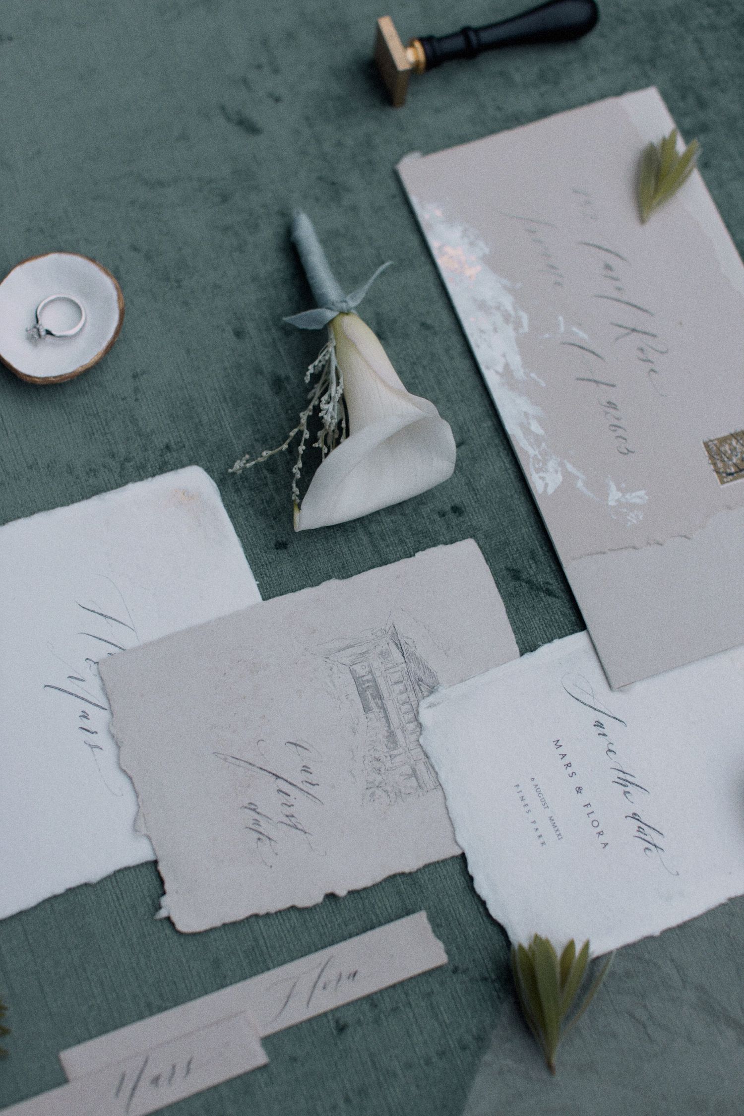 Wedding invitations and white flowers arranged on a dark surface with elegant calligraphy.