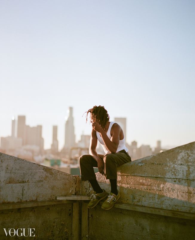 Silhouette of person sitting on urban rooftop against city skyline at dusk.