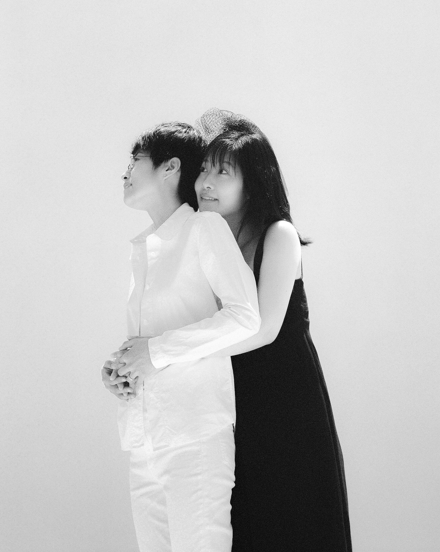An artistic black and white portrait of a couple embracing in minimalist clothing.