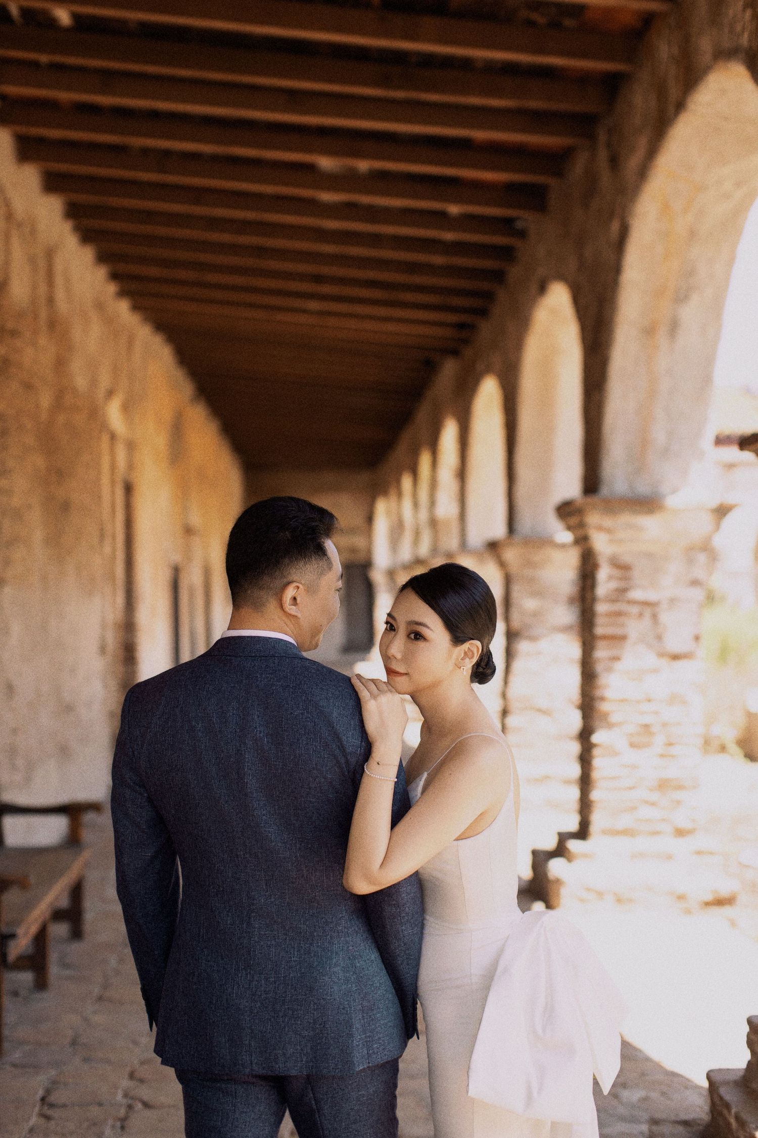 A tender moment between newlyweds under a rustic columned archway.