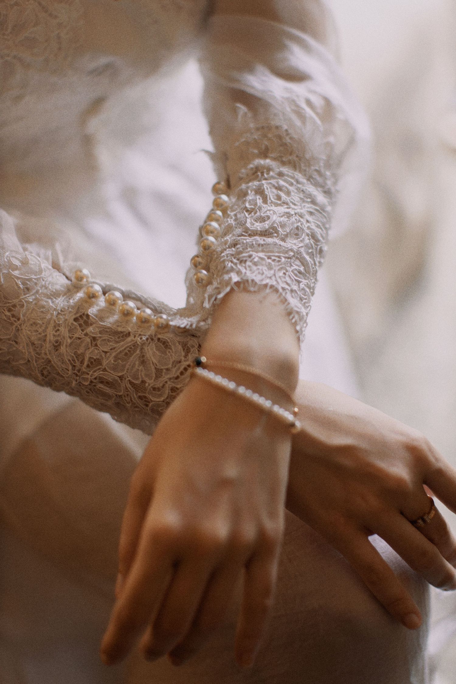 Close-up detail of delicate lace sleeve and bracelet on a bride's wrist.