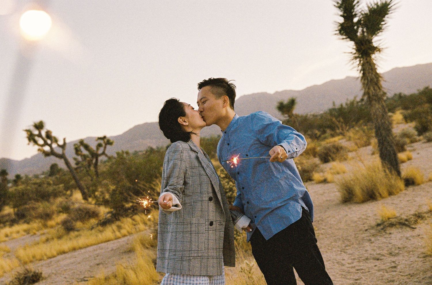 A couple enjoys a playful moment together in the desert at golden hour.