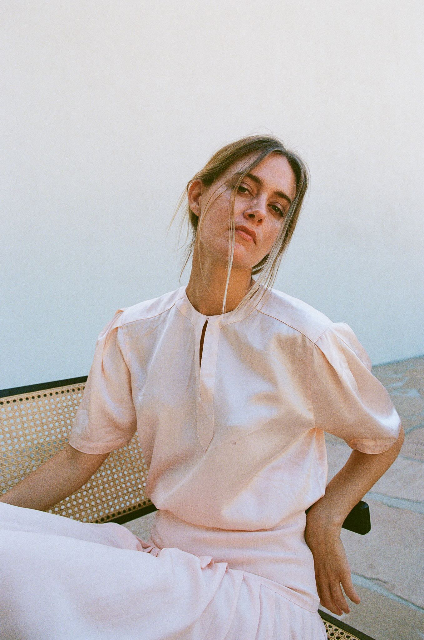 A romantic portrait showcasing a light pink puff-sleeve dress against a minimal background.