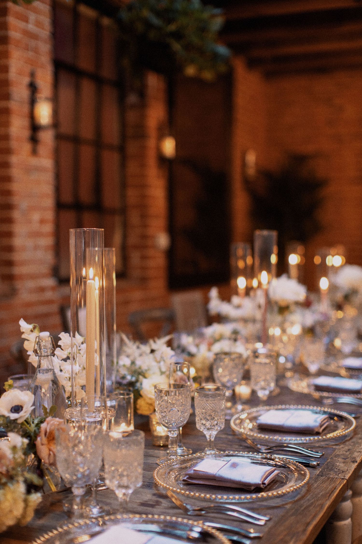 Elegant wedding table setting with crystal glasses, candles and white floral centerpieces.