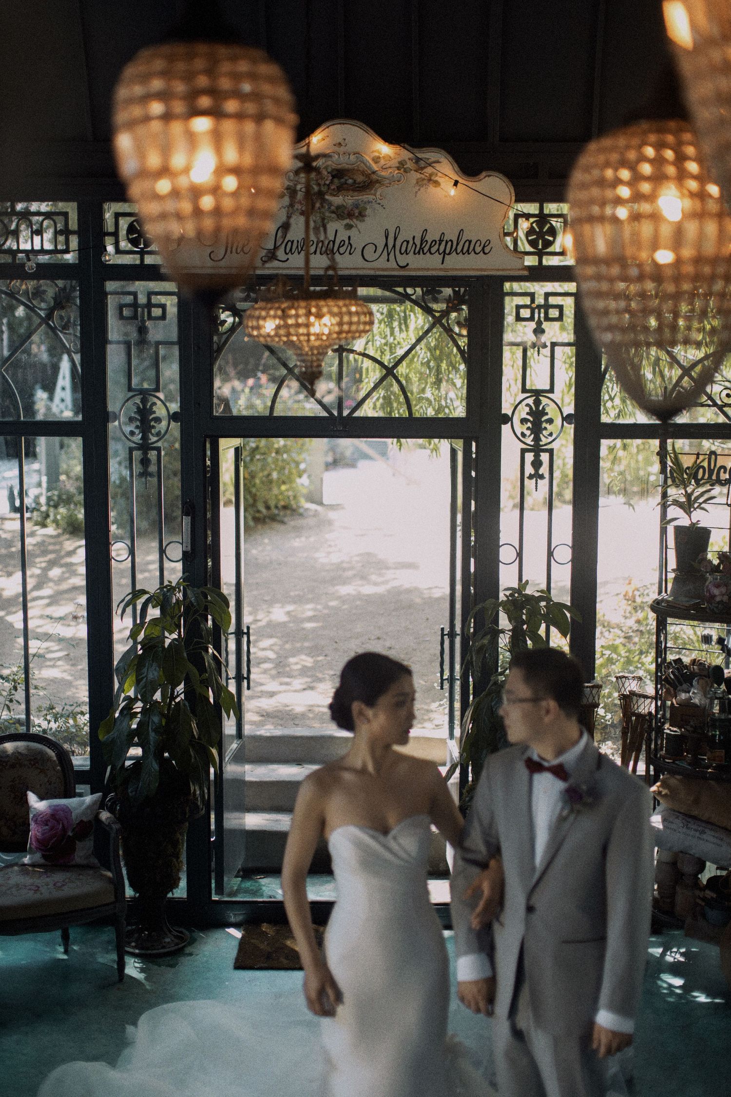 Wedding scene in vintage venue with ornate windows and hanging lantern decor.