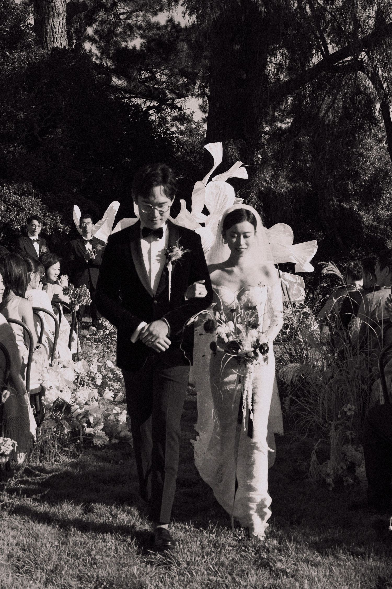 A black and white wedding ceremony photo in a garden setting.
