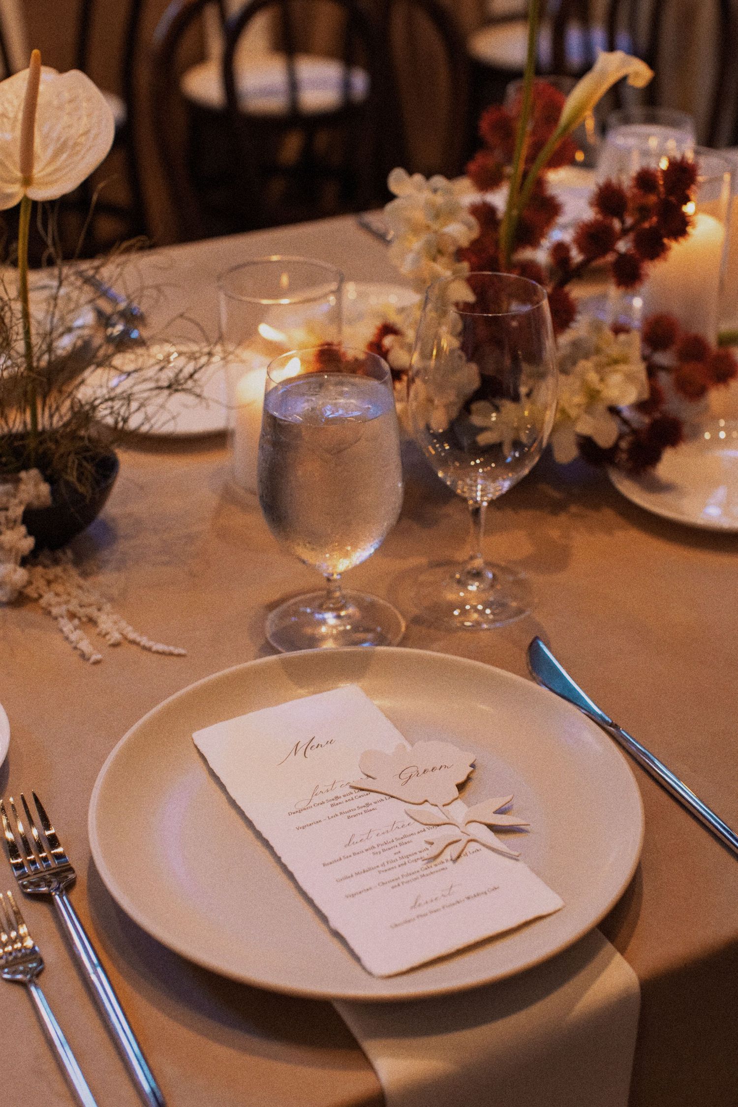 Elegant wedding table setting with menu card, wine glasses, and floral centerpieces.