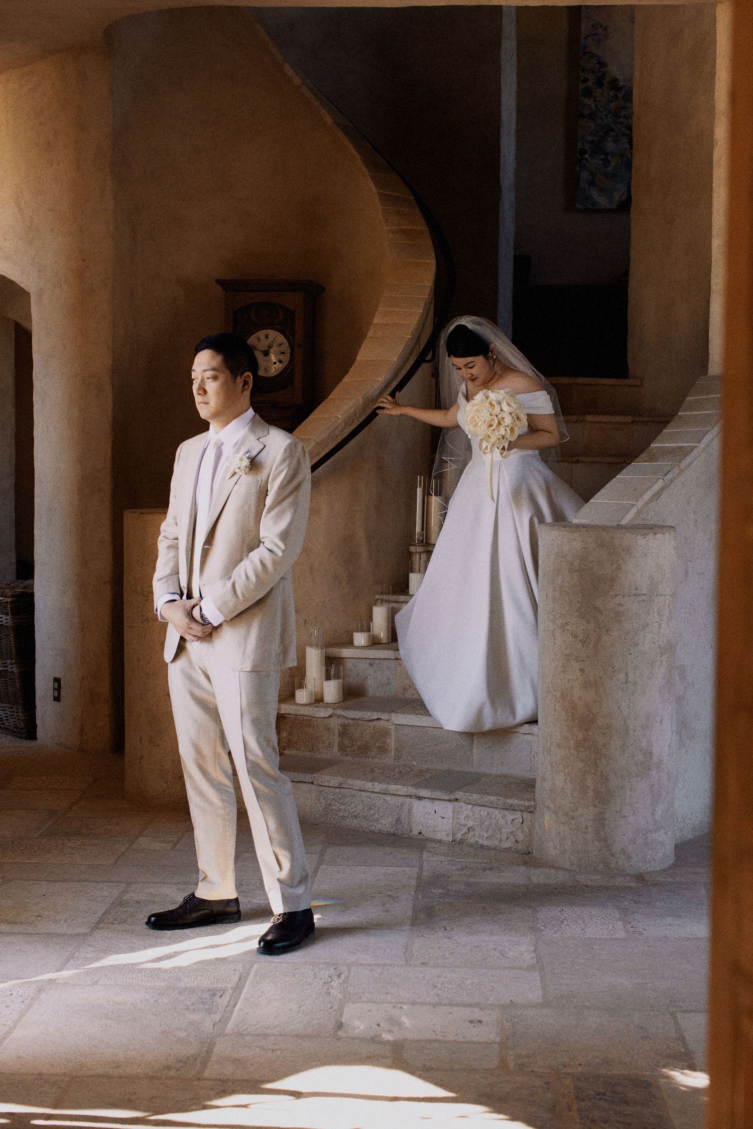 A traditional first look moment captured between a couple on an elegant stone staircase.
