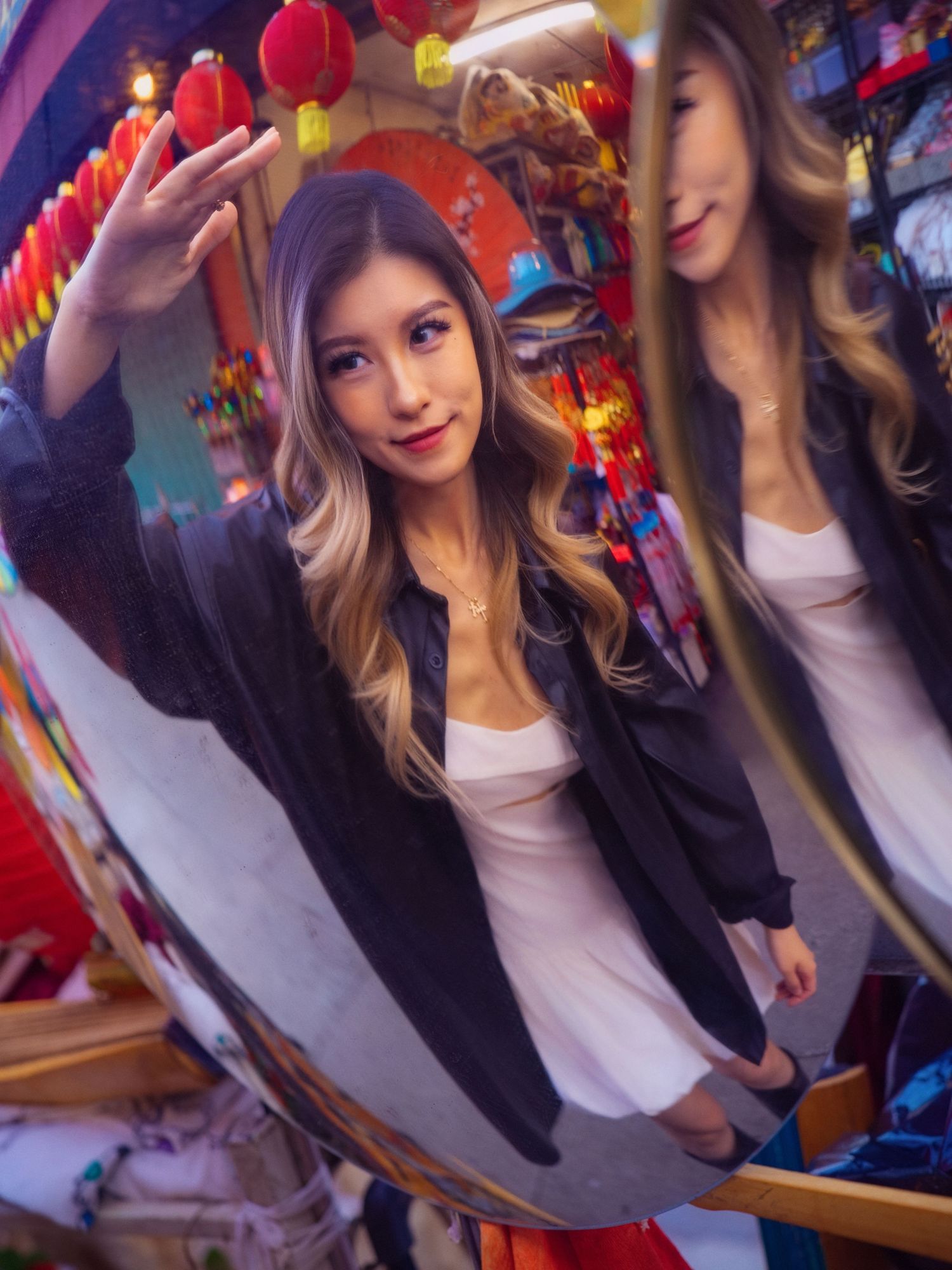 Model poses with reflective mirror effect under red Chinese lantern decorations.