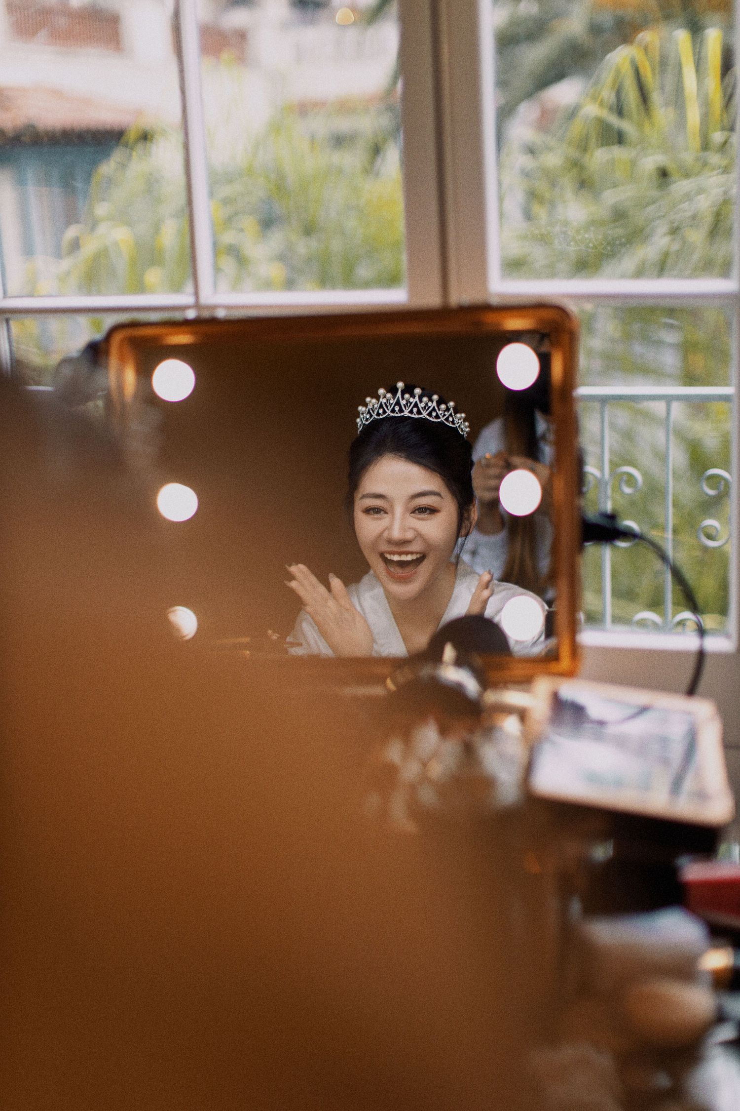 A reflection in a vanity mirror shows a bride wearing a sparkling tiara.