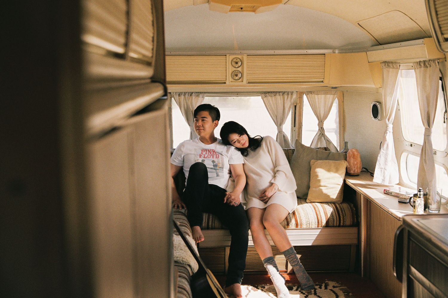 Couple relaxing inside vintage camper van with warm interior lighting.