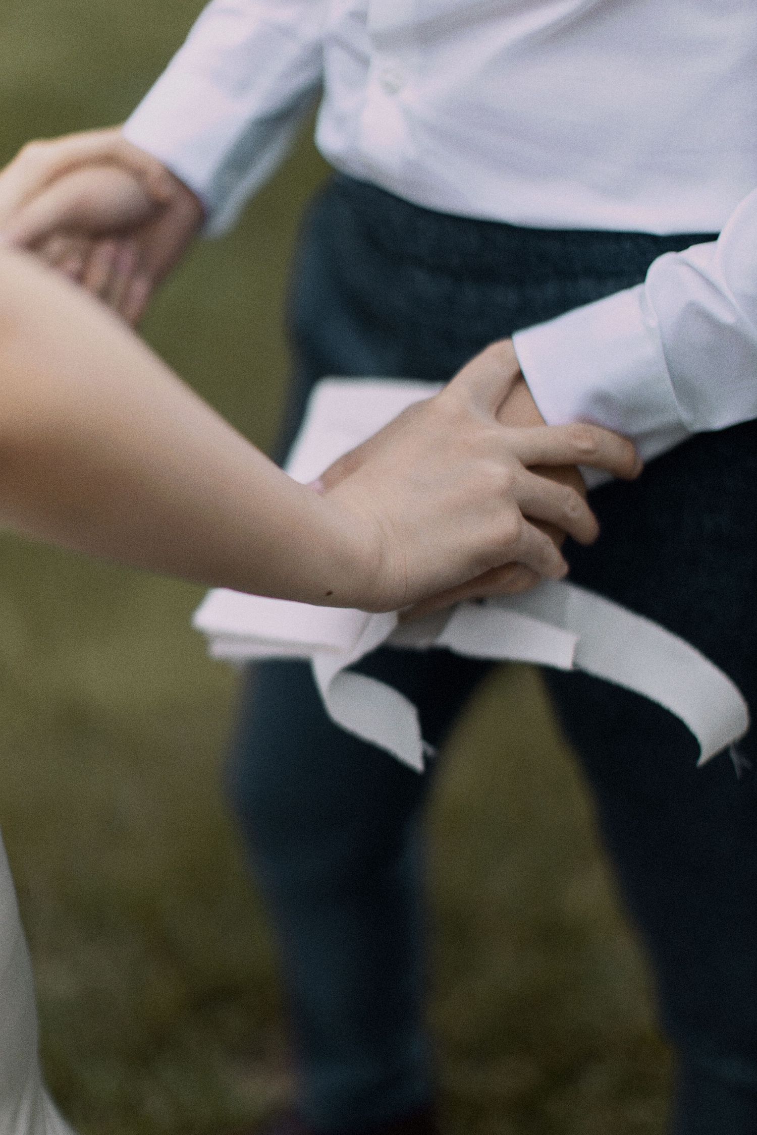Close-up of hands grasping white fabric against casual attire.