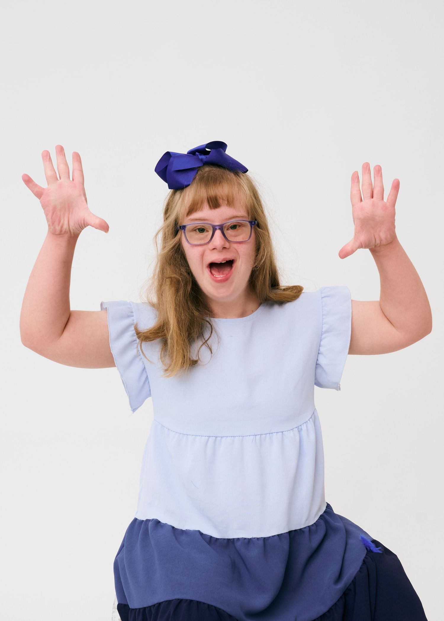 A playful series of poses in a light blue dress and navy bow headband against a white background.