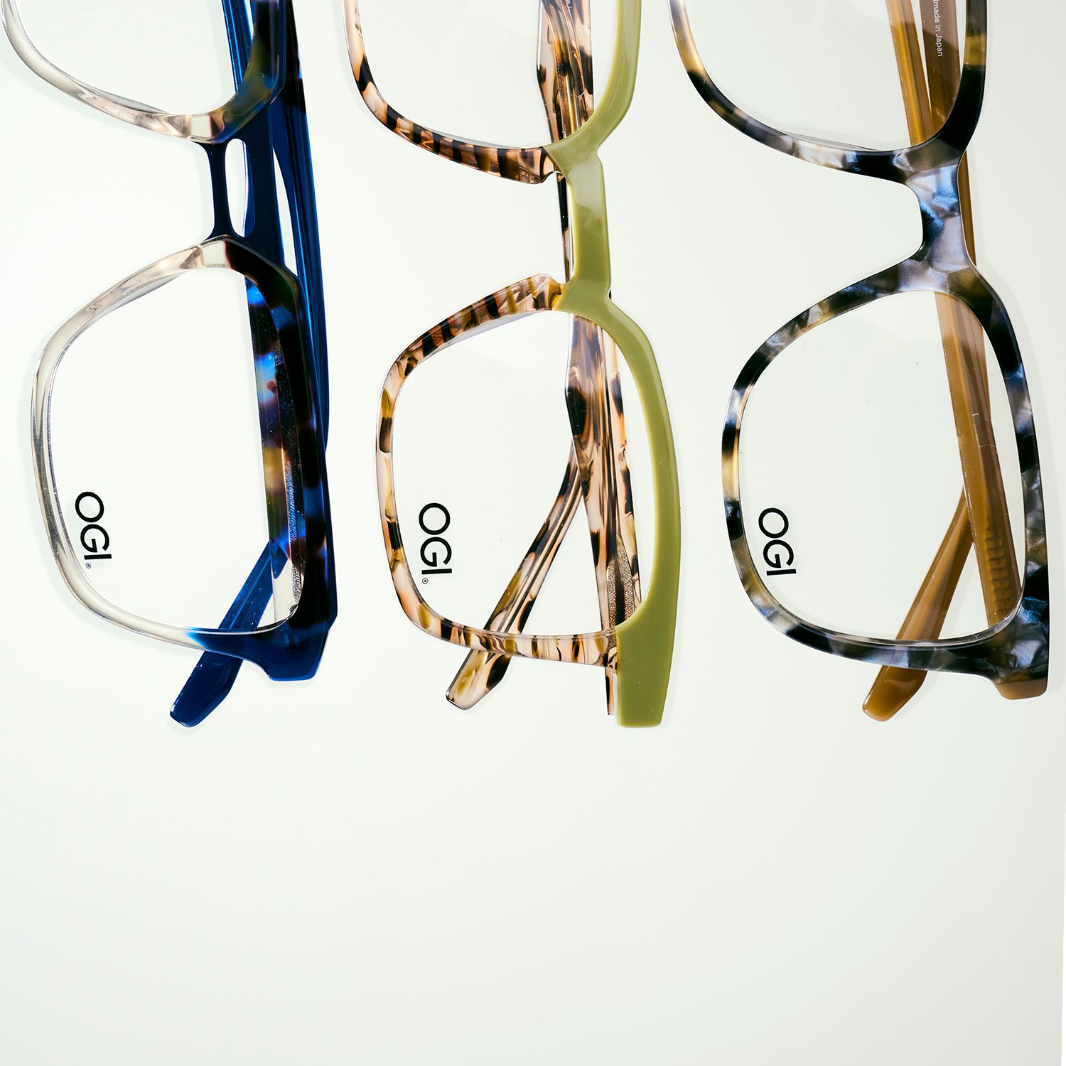Three stylish eyeglass frames in blue, tortoise, and silver arranged in a row.