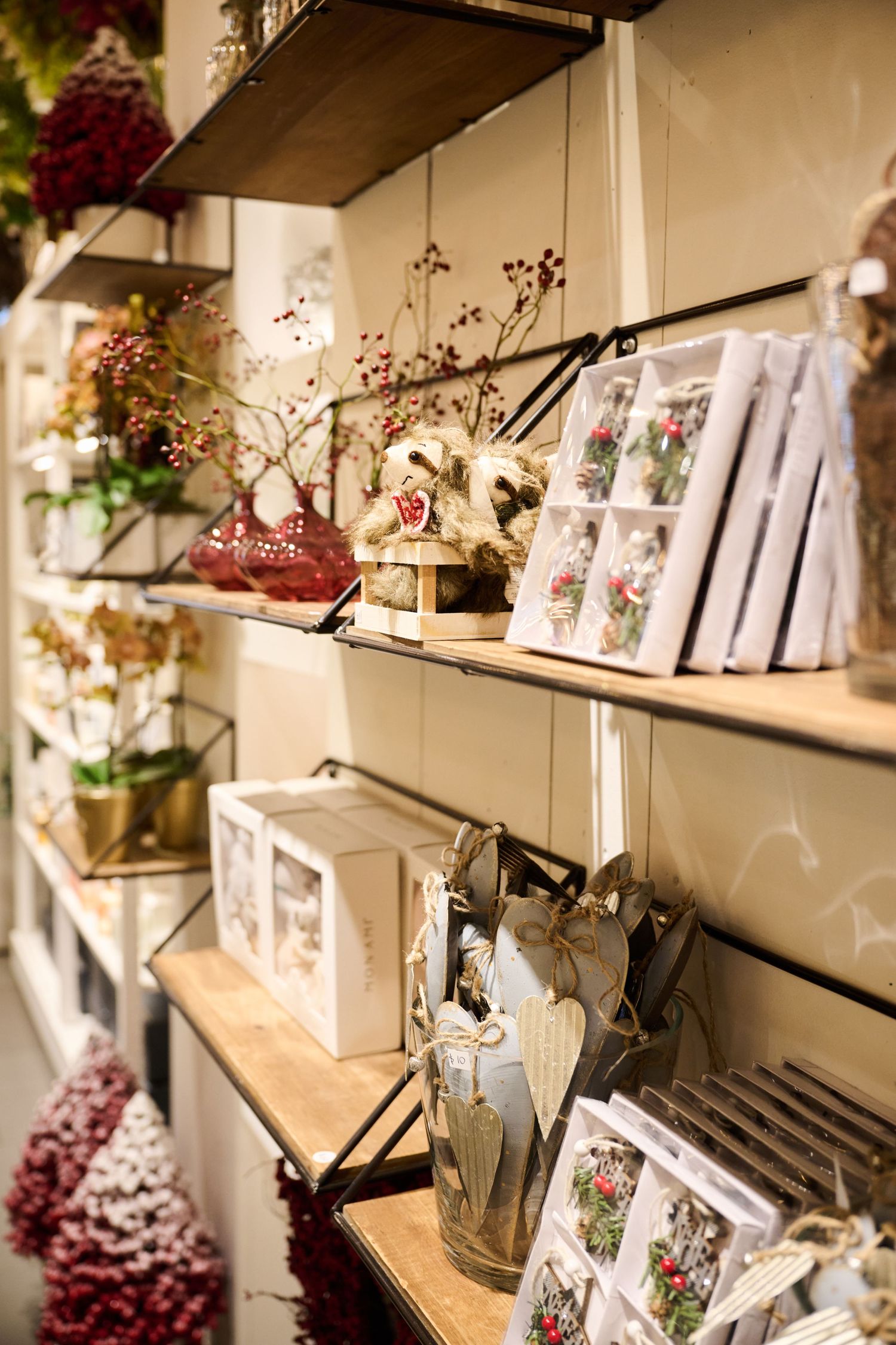 Rustic retail display shelves featuring floral greeting cards, glass vases, and dried flower arrangements.