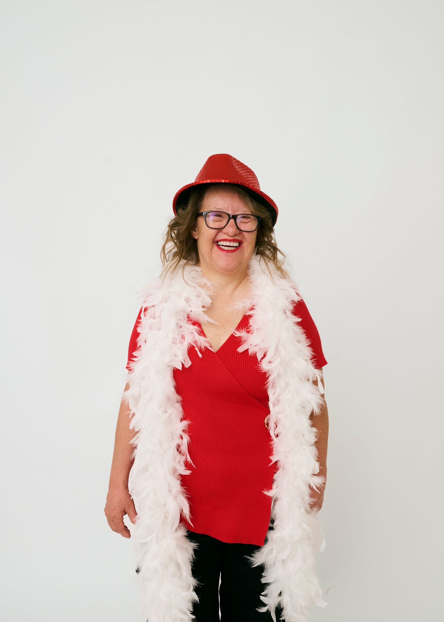A festive outfit featuring a red shirt, white feather boa, and red hat against a white background.