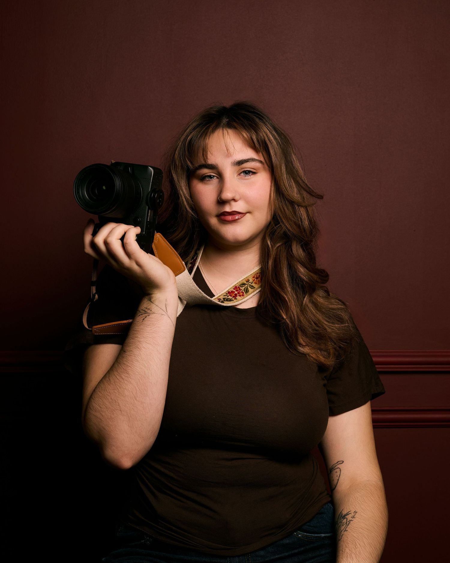 A figure in a black top poses against a dark brown backdrop in a series of dramatic studio portraits.