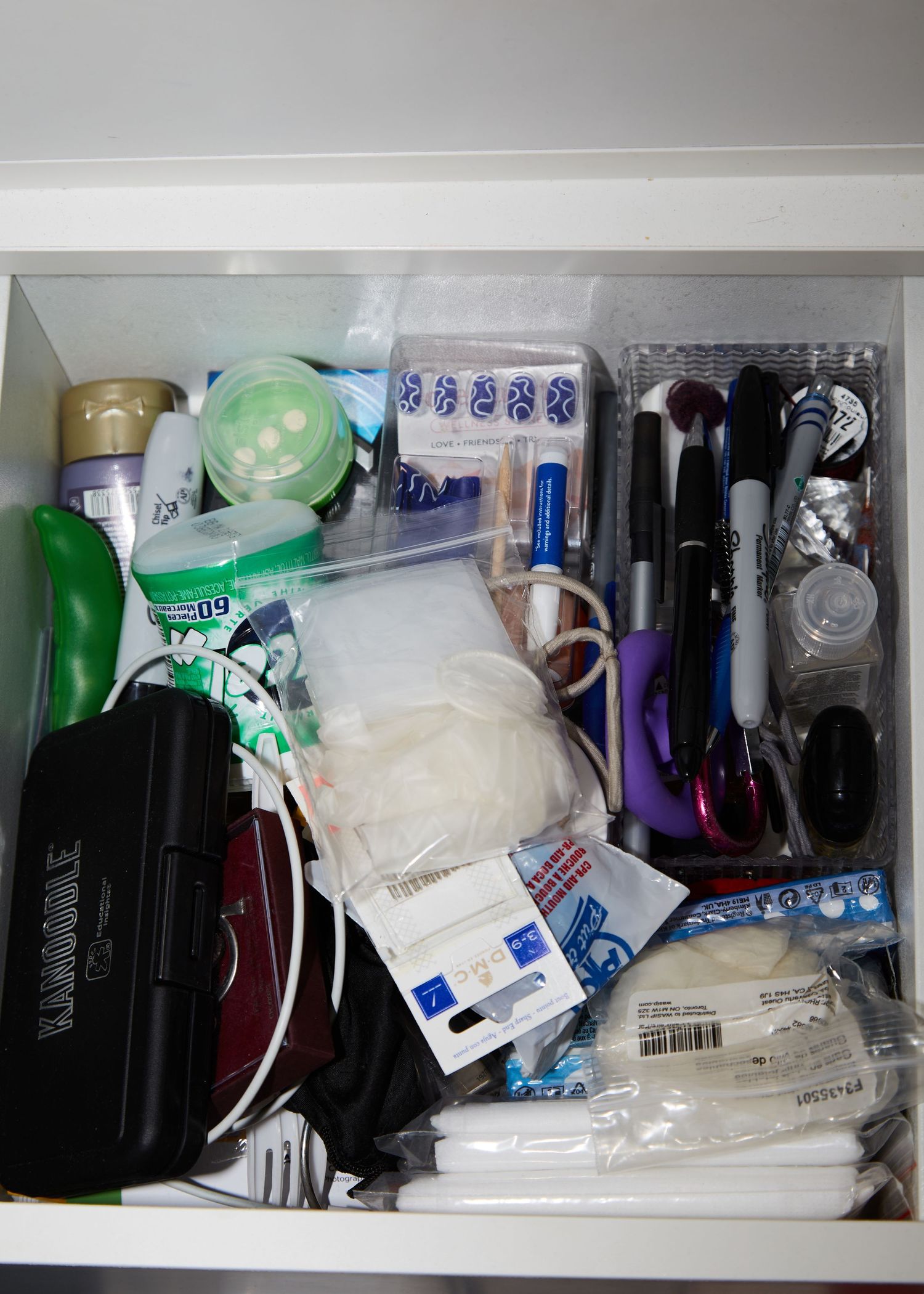 Drawer filled with various personal care items, pens, and miscellaneous supplies.