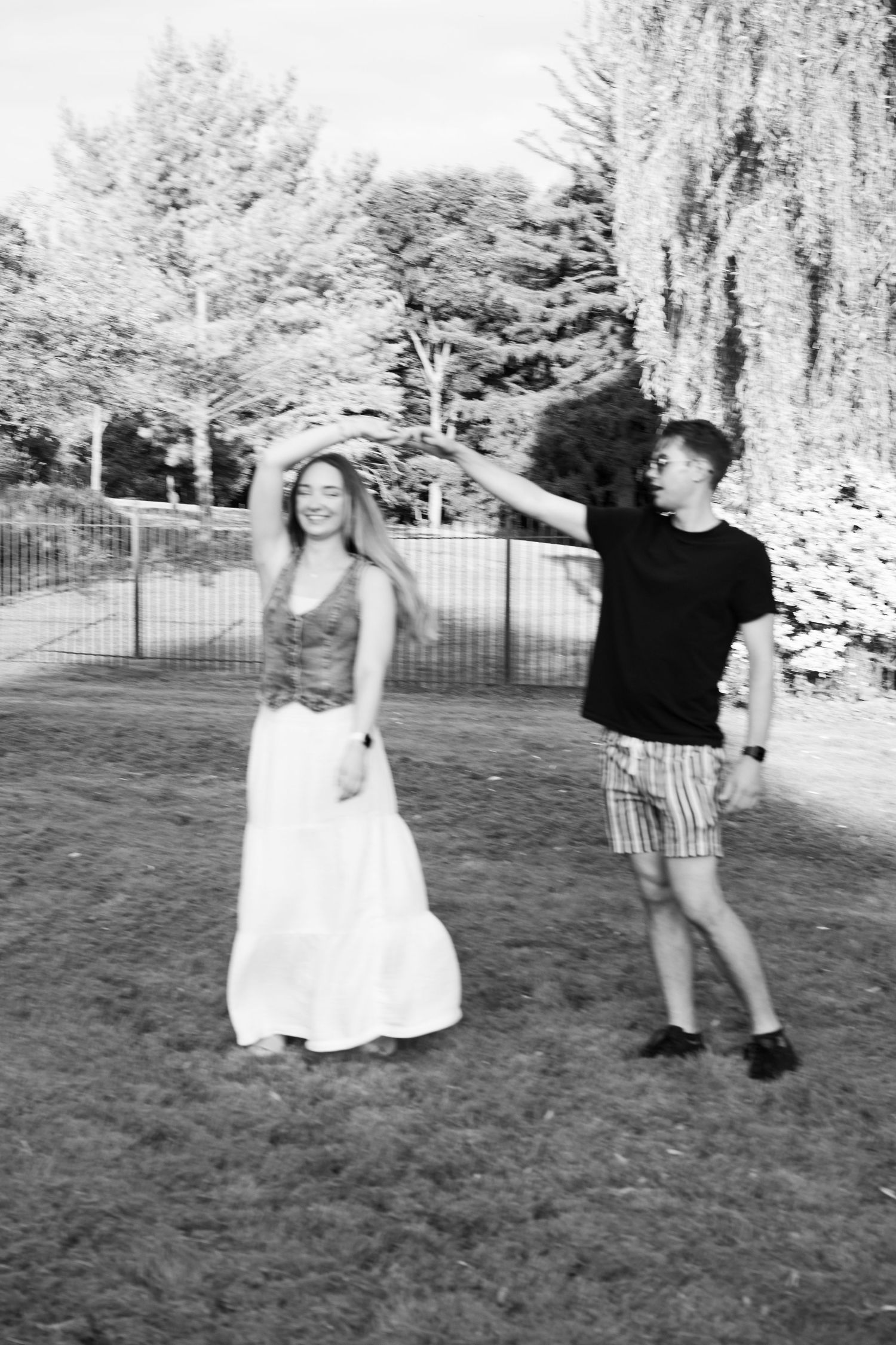 A playful sequence of black and white photos showing a couple dancing together on a grassy lawn.