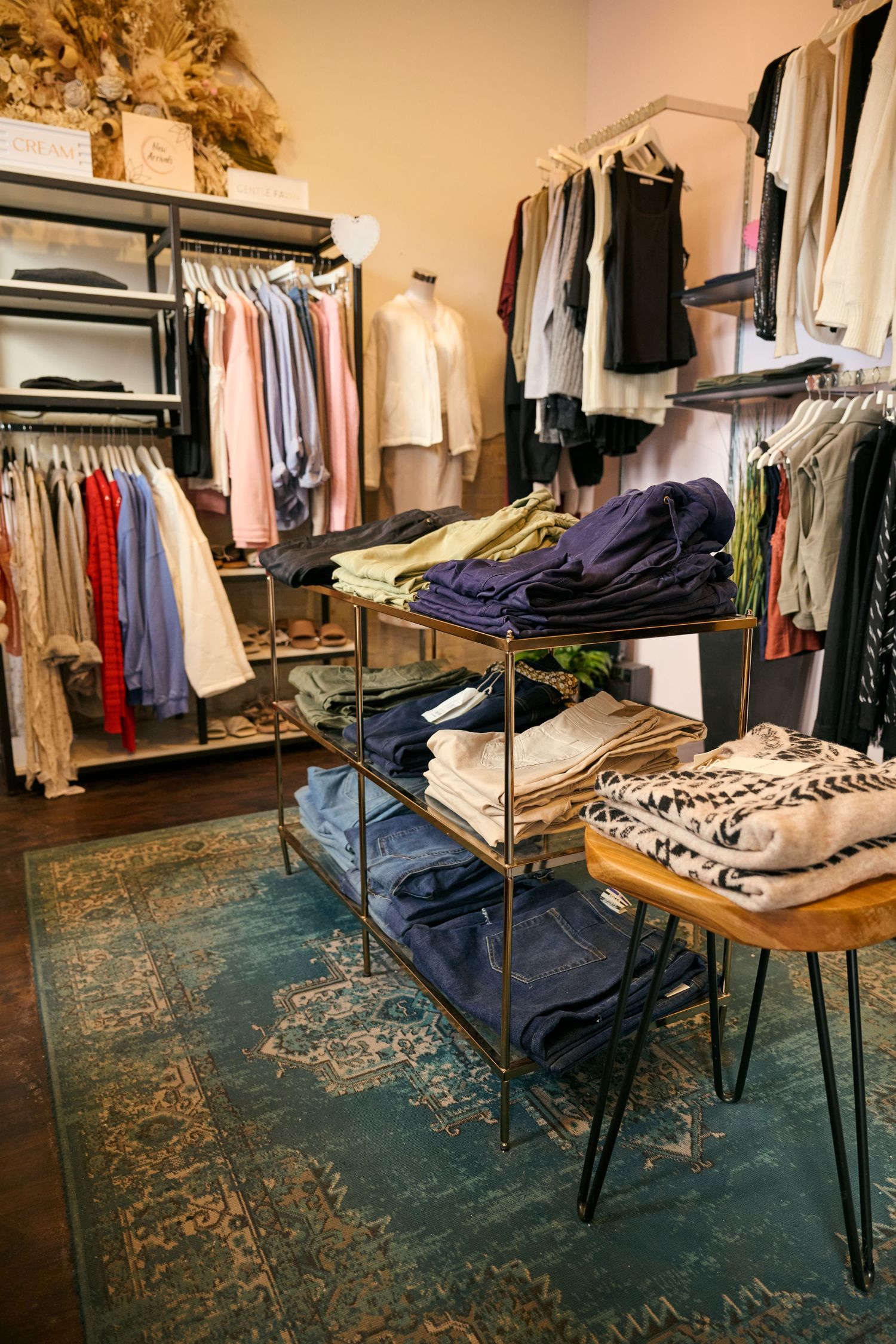 Organized retail display with clothing racks, folded denim, and patterned garments on industrial shelving.