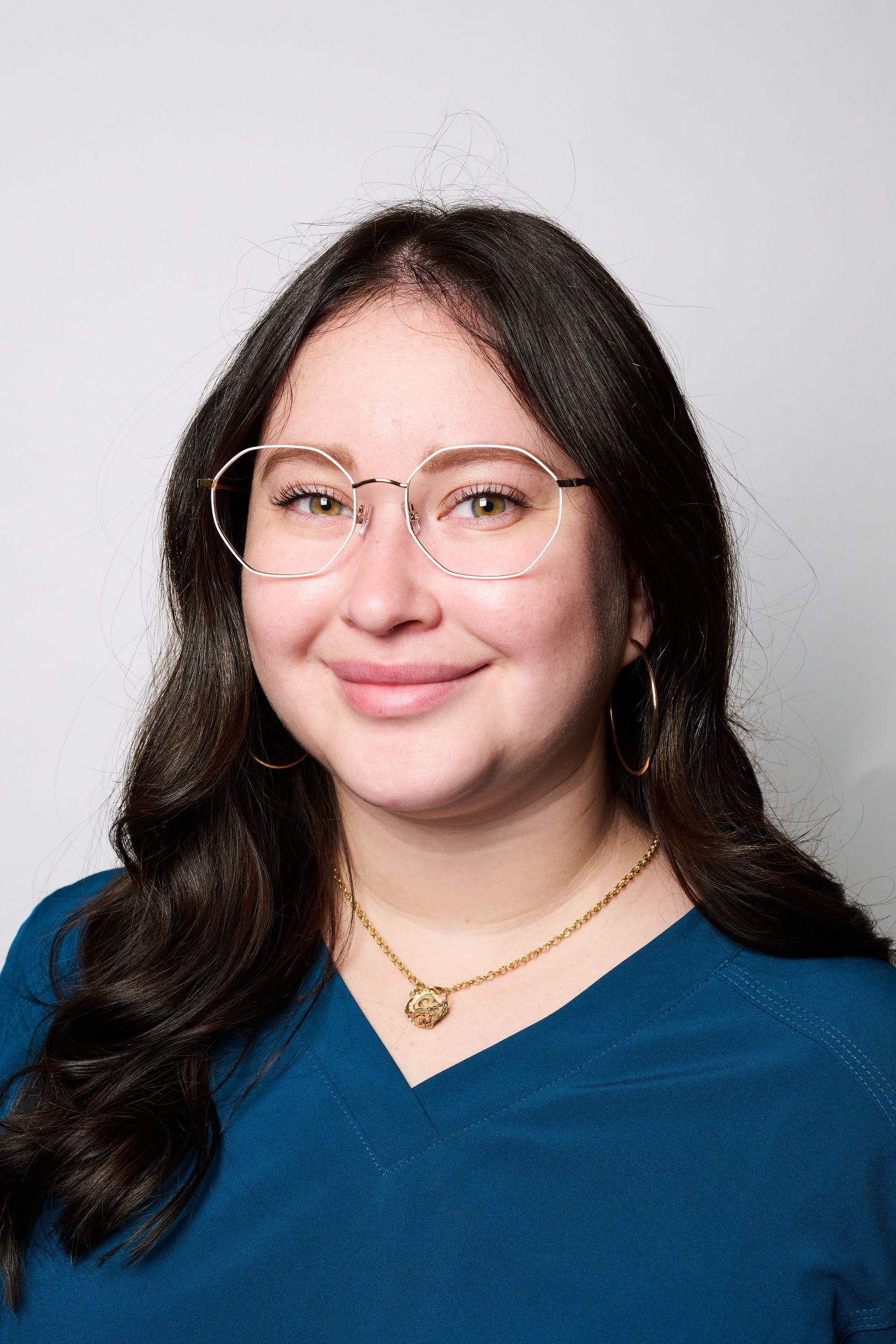 A series of headshots showing someone in a navy blue top and gold necklace against a light background.