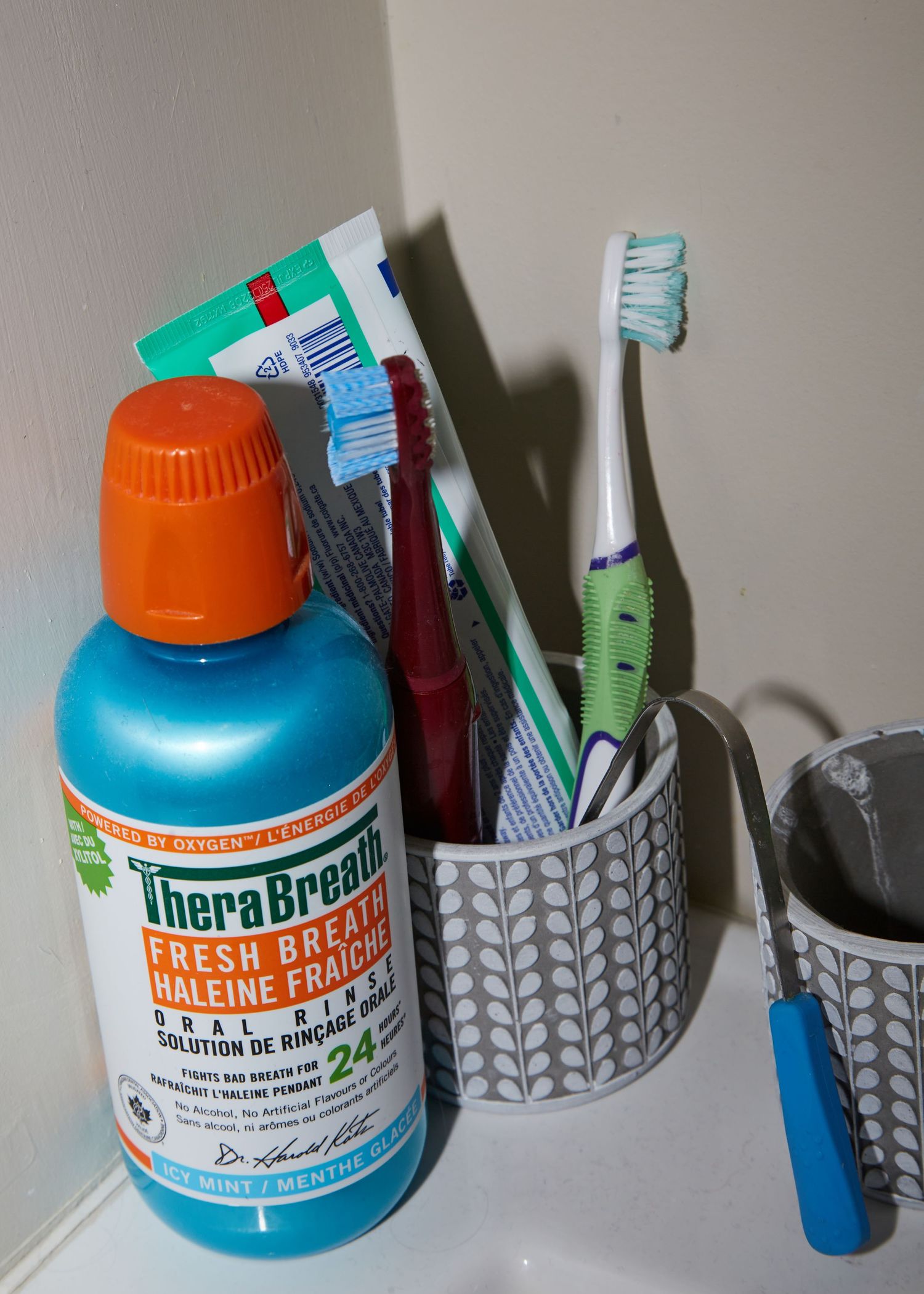 A bathroom counter with toothbrushes and mouthwash in patterned holders.