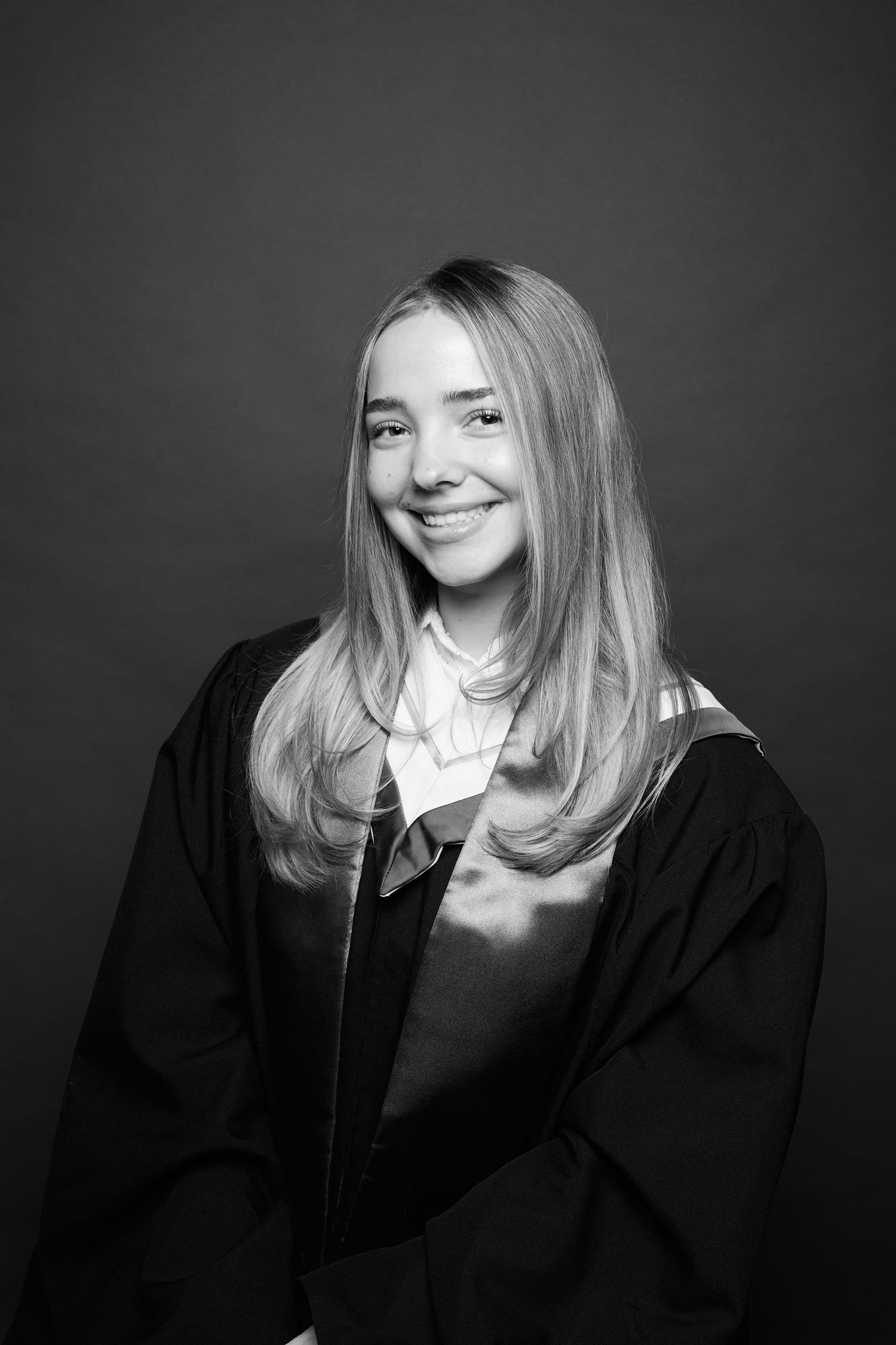 A series of black and white portraits showing someone in graduation attire with blonde hair smiling at the camera.
