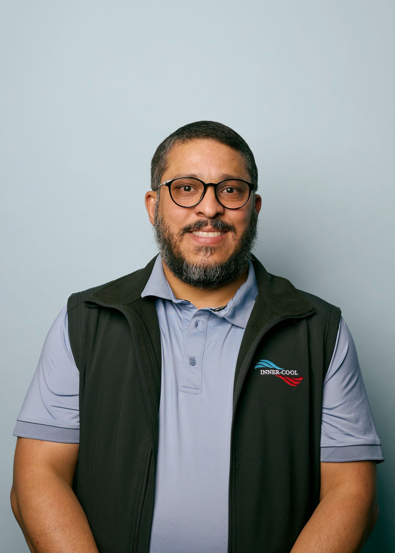 Corporate portraits featuring someone wearing a gray polo and black vest against a light backdrop.