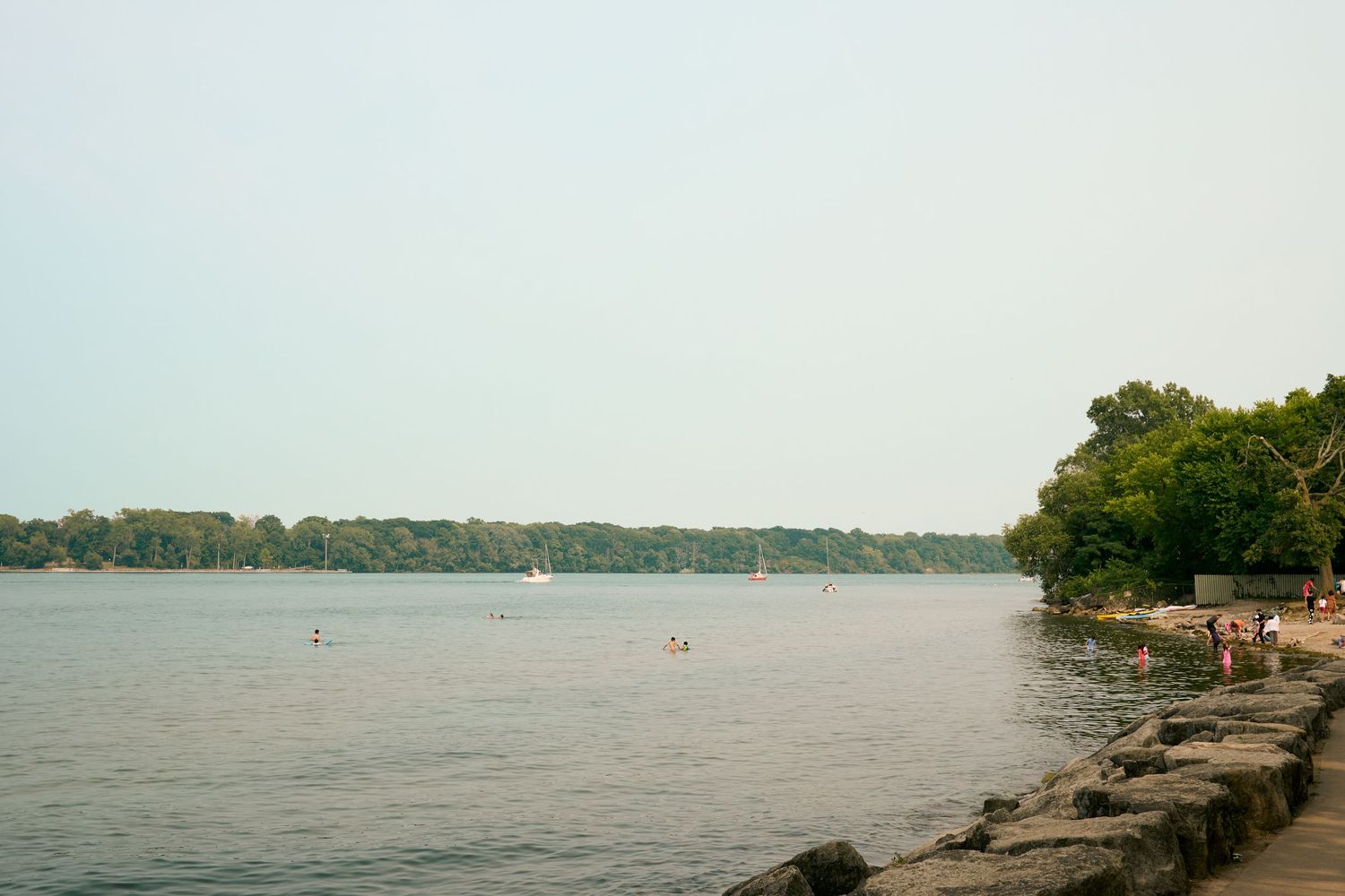 A scenic montage showing multiple views of a shoreline with trees, rocky outcrops, and calm water stretching to the horizon.