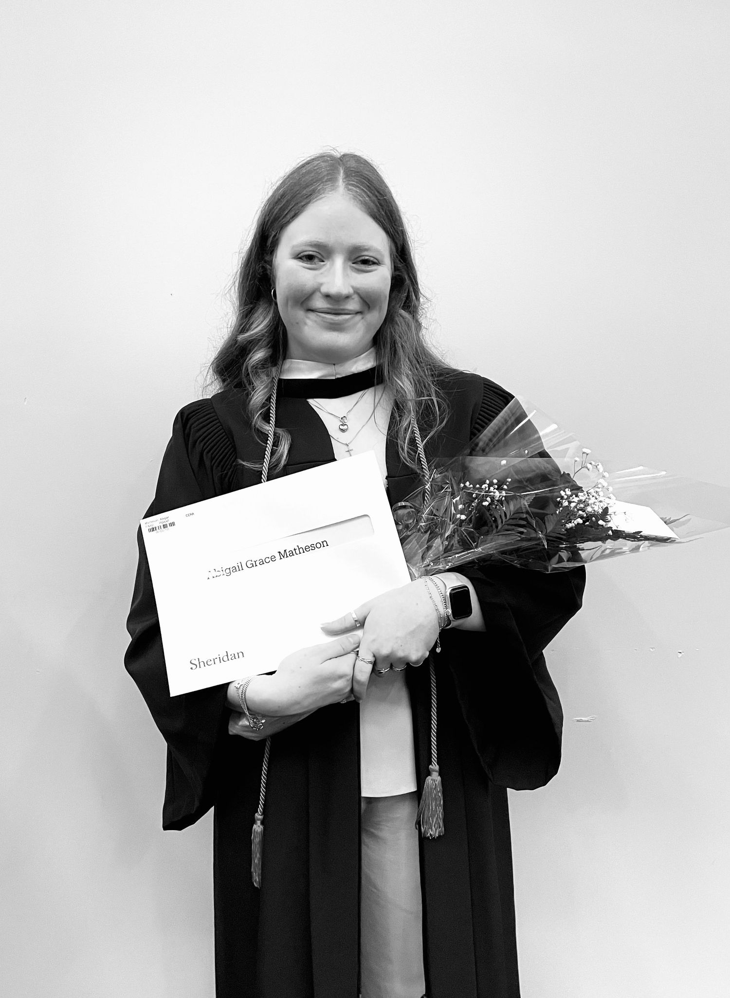 A sequence of four black and white photos shows someone in graduation attire tearing up a piece of paper with increasing emotion.