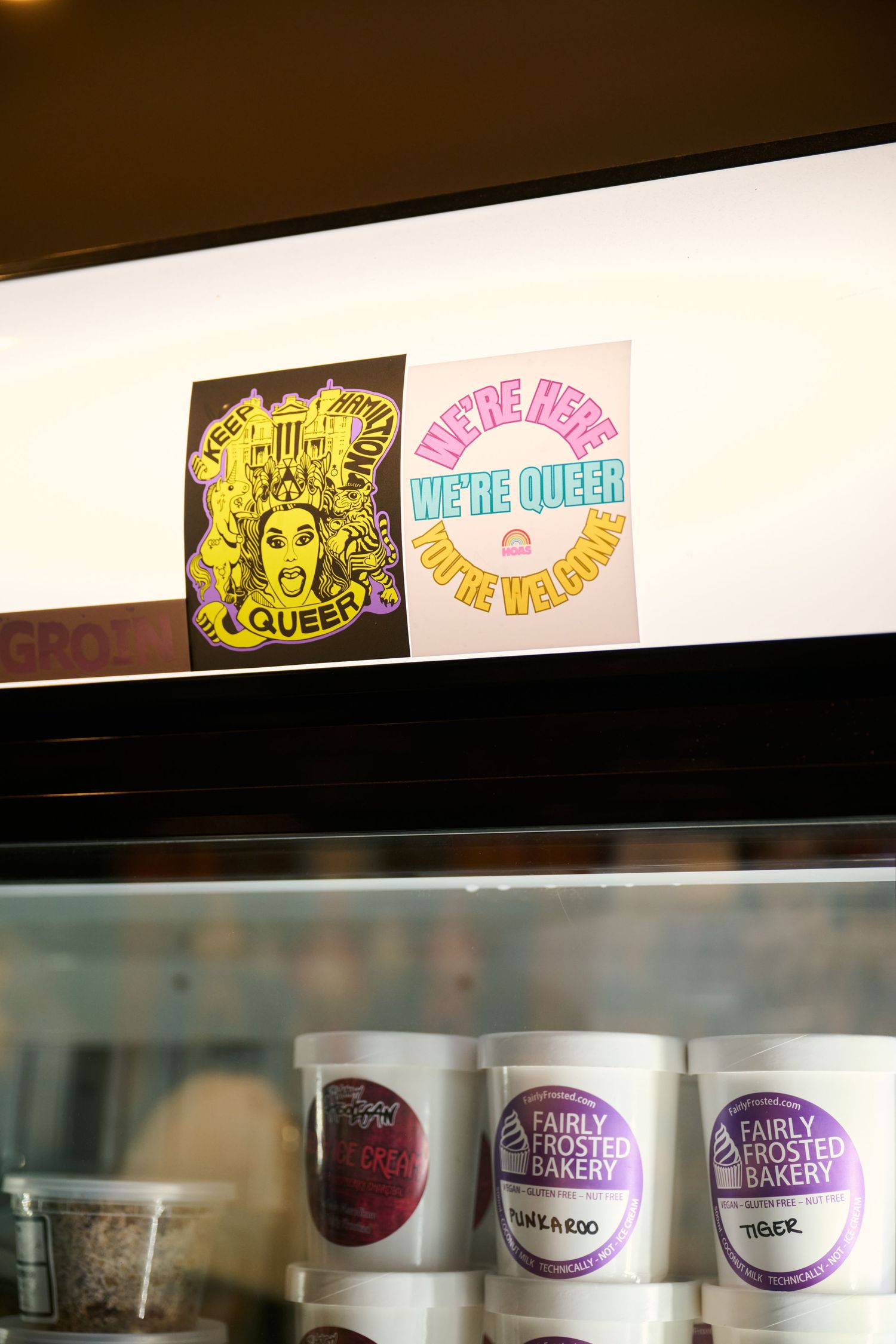 Two decorative stickers with queen-themed designs displayed above storage containers in a restaurant setting.