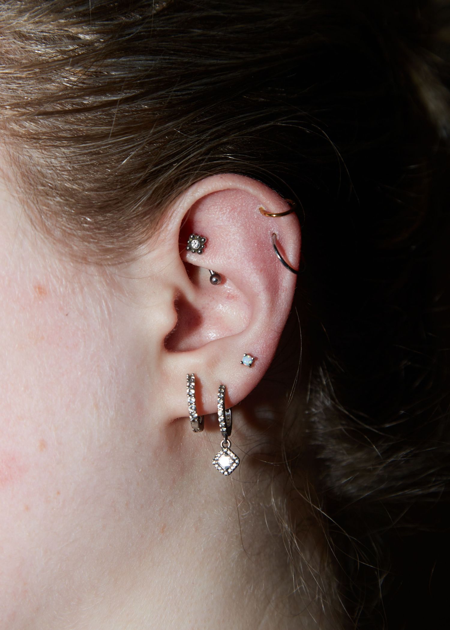Close-up of multiple ear piercings with diamond and silver jewelry.