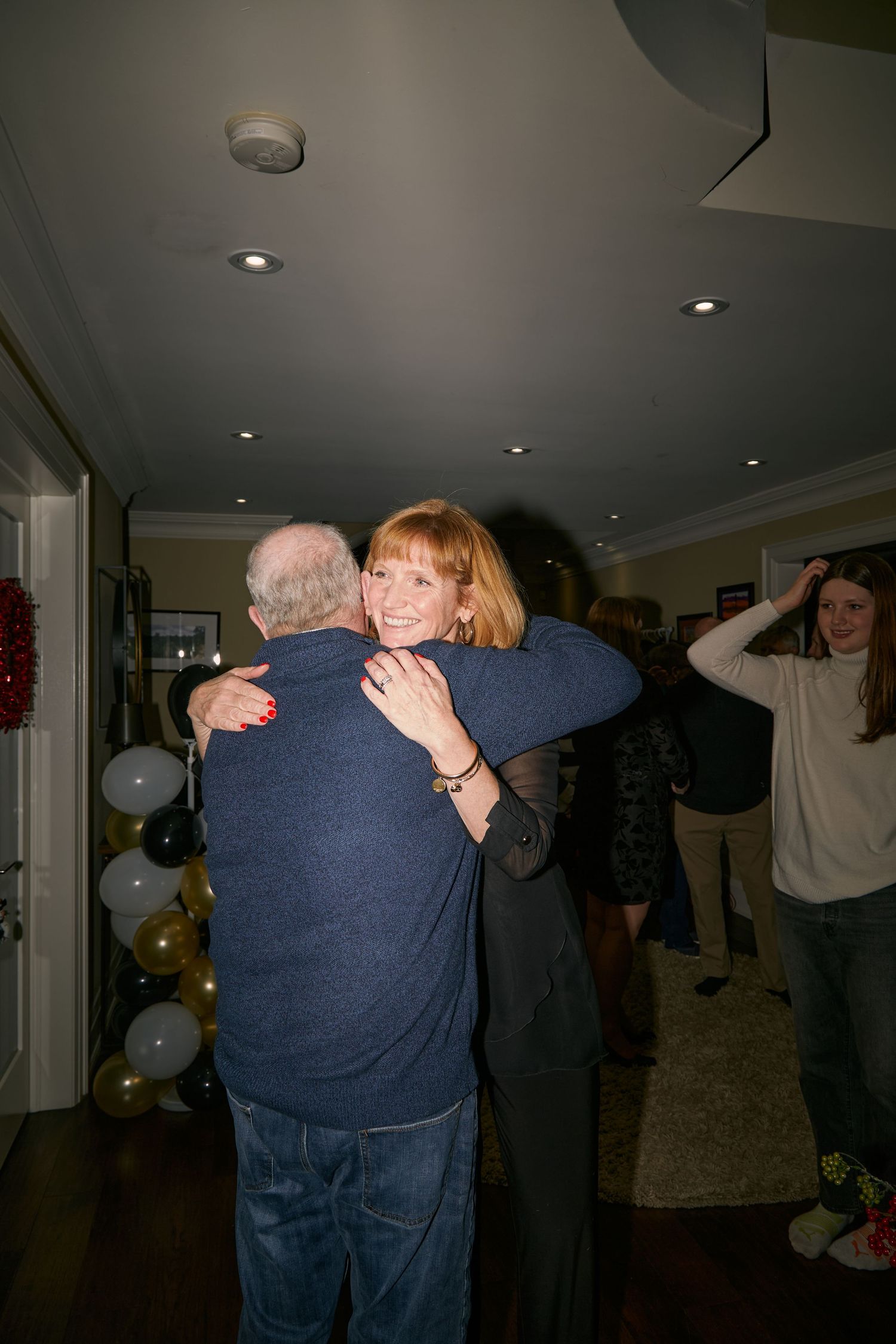 A sequence of photos showing two people embracing warmly in a dimly lit indoor setting with balloons in the background.