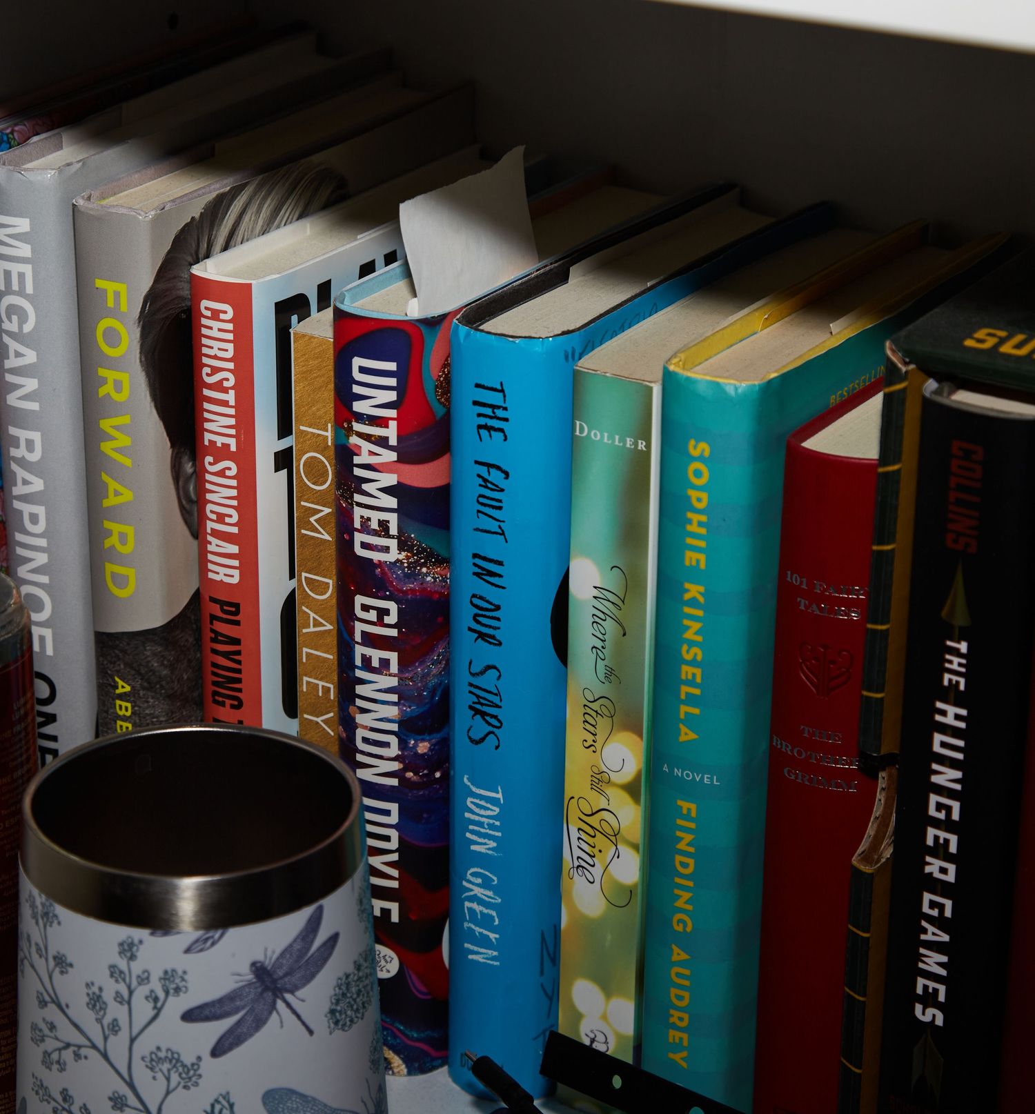 Bookshelf with colorful book spines and a decorative mug.