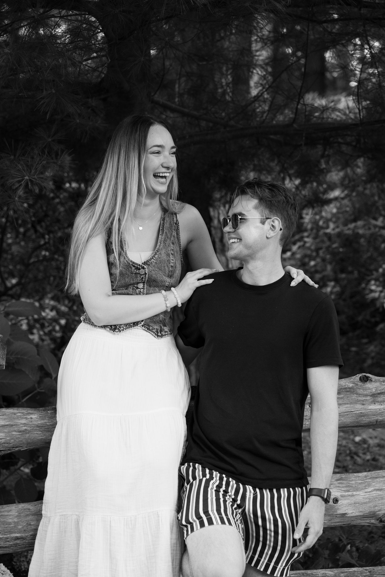 Candid black and white photo of a couple laughing together on a rock formation.