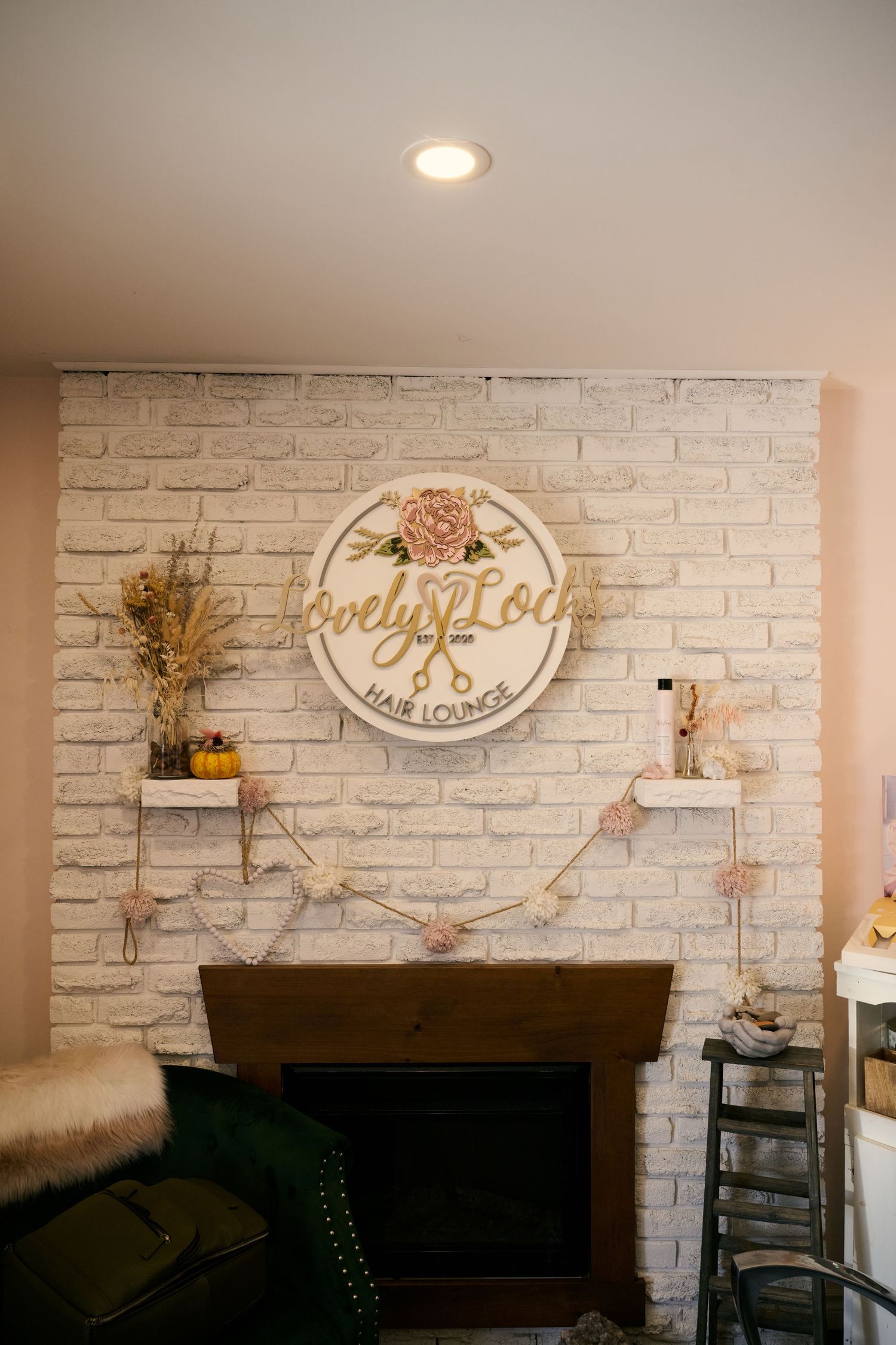 A cozy living room wall featuring a white brick fireplace with circular decorative sign and dried flower accents.